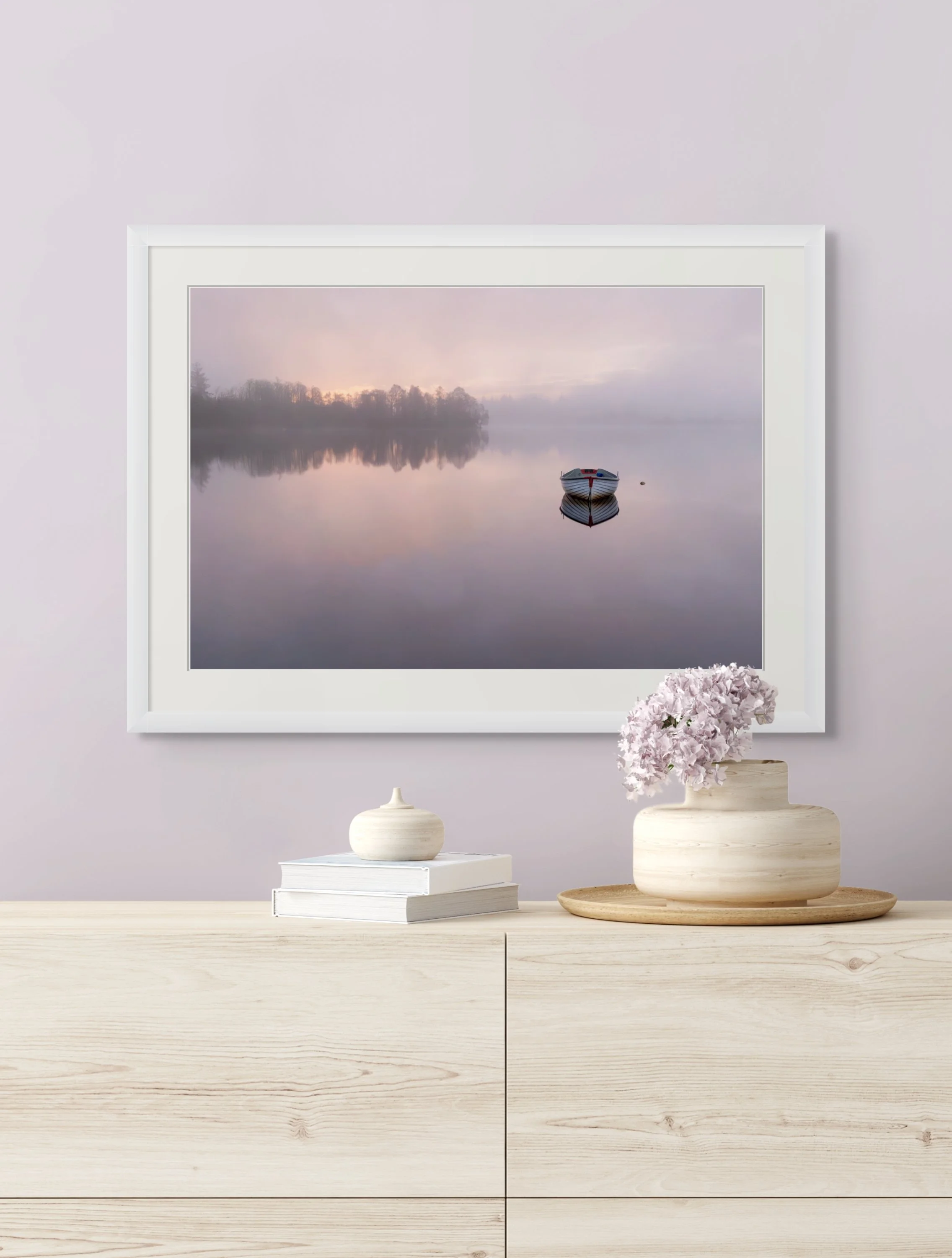 a fine art photograph of a sunrise misty loch, pink and hazy with a boat, above a sideboard with ornaments