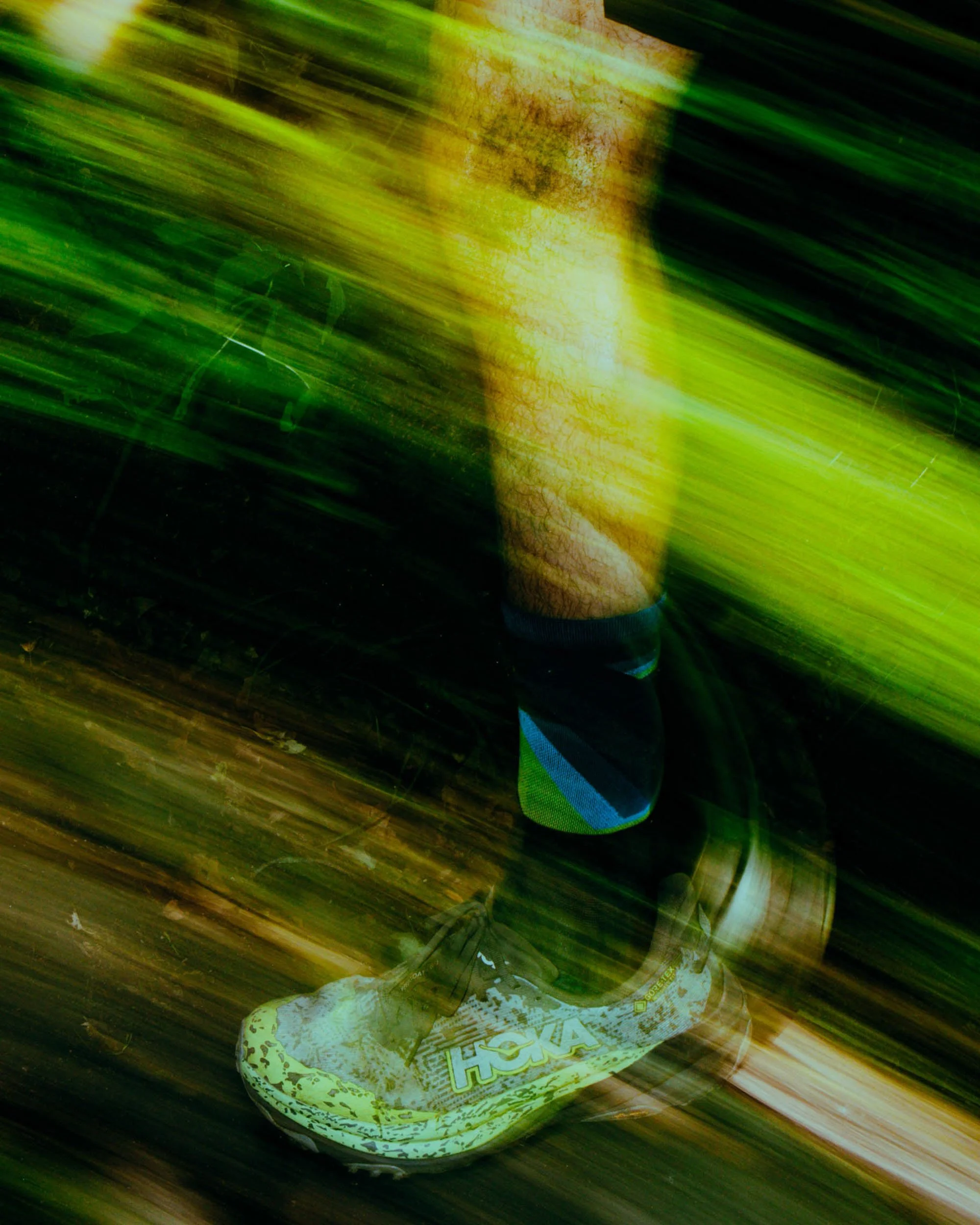 A person wearing a glove is using a spray bottle to spray a cleaning solution on a white hoverboard with a yellow camouflage pattern on its surface, placed on a wooden floor. The scene is spread with green and yellow light streaks.