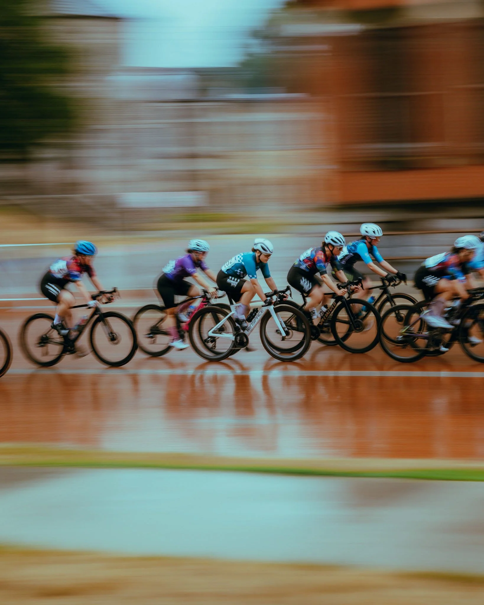 A group of cyclists riding on a course, with a blurred background indicating motion and speed.