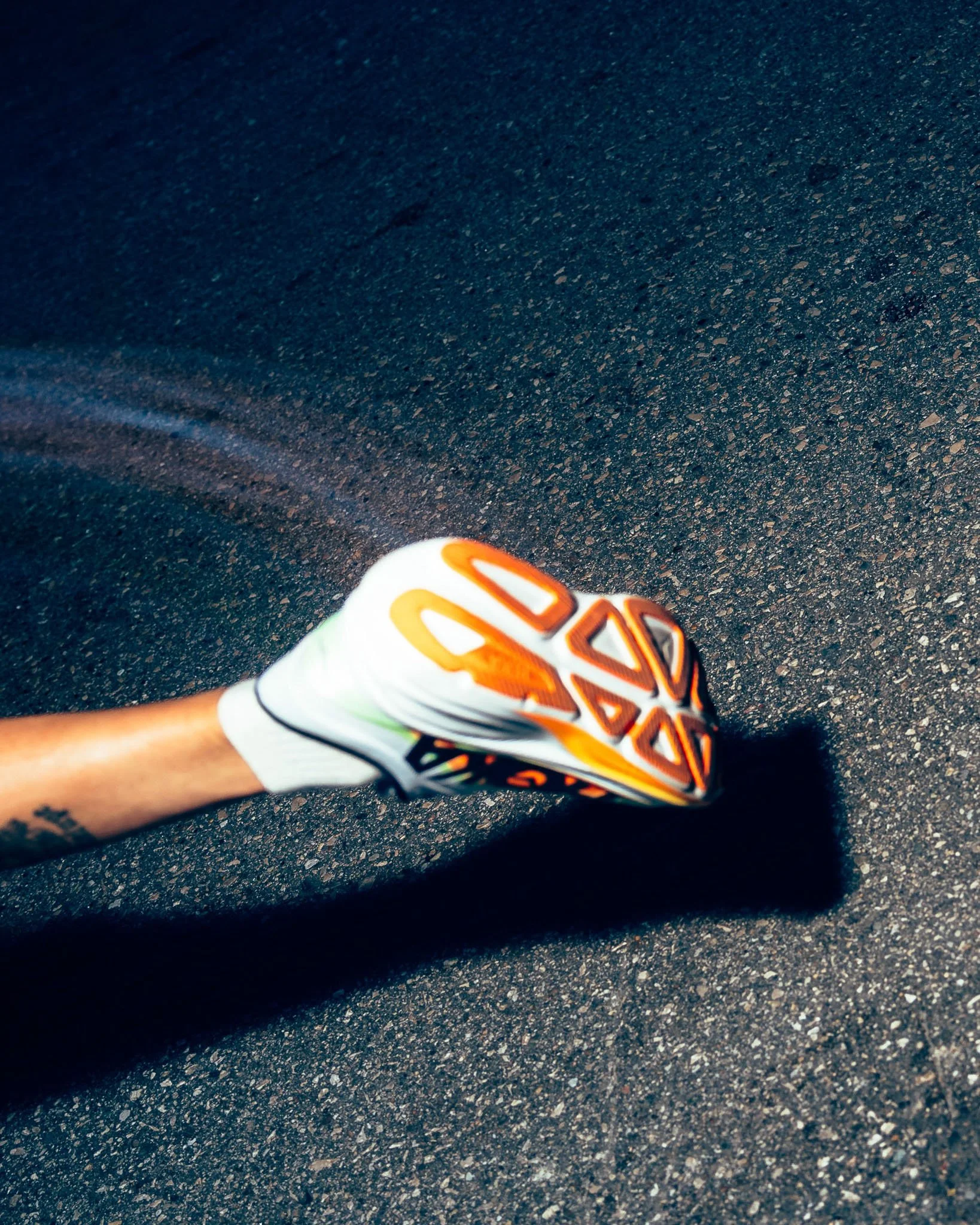 Close-up of a running shoe in motion on a textured asphalt surface.