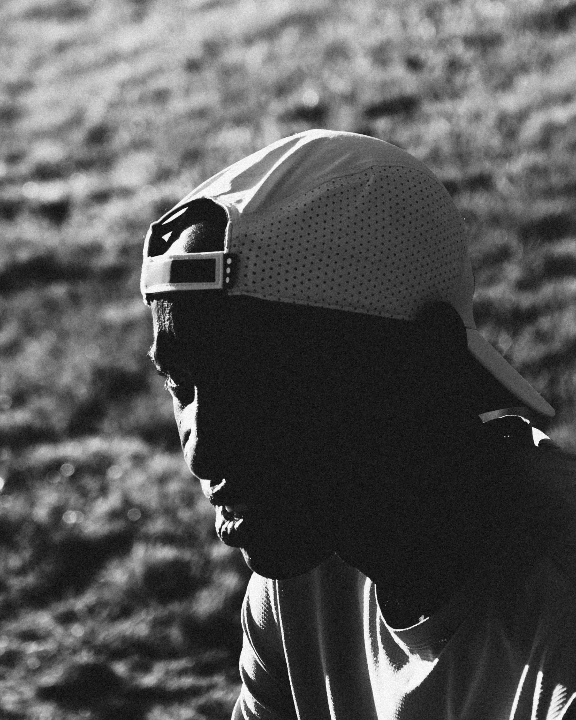Close-up of a person wearing a sports cap and athletic clothing, with a grassy field in the background.
