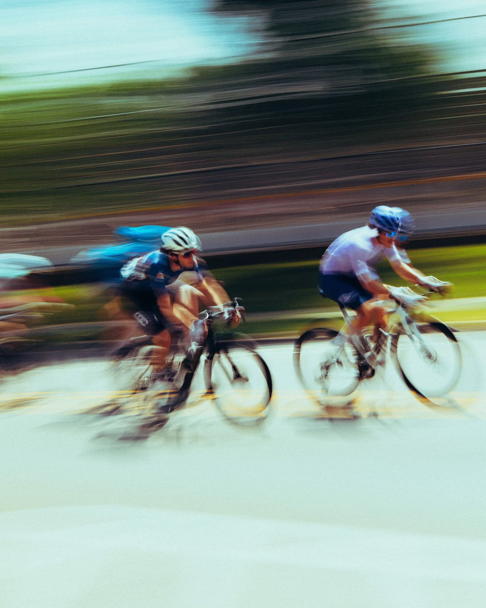Two cyclists racing on a road, with a motion blur background indicating high speed.