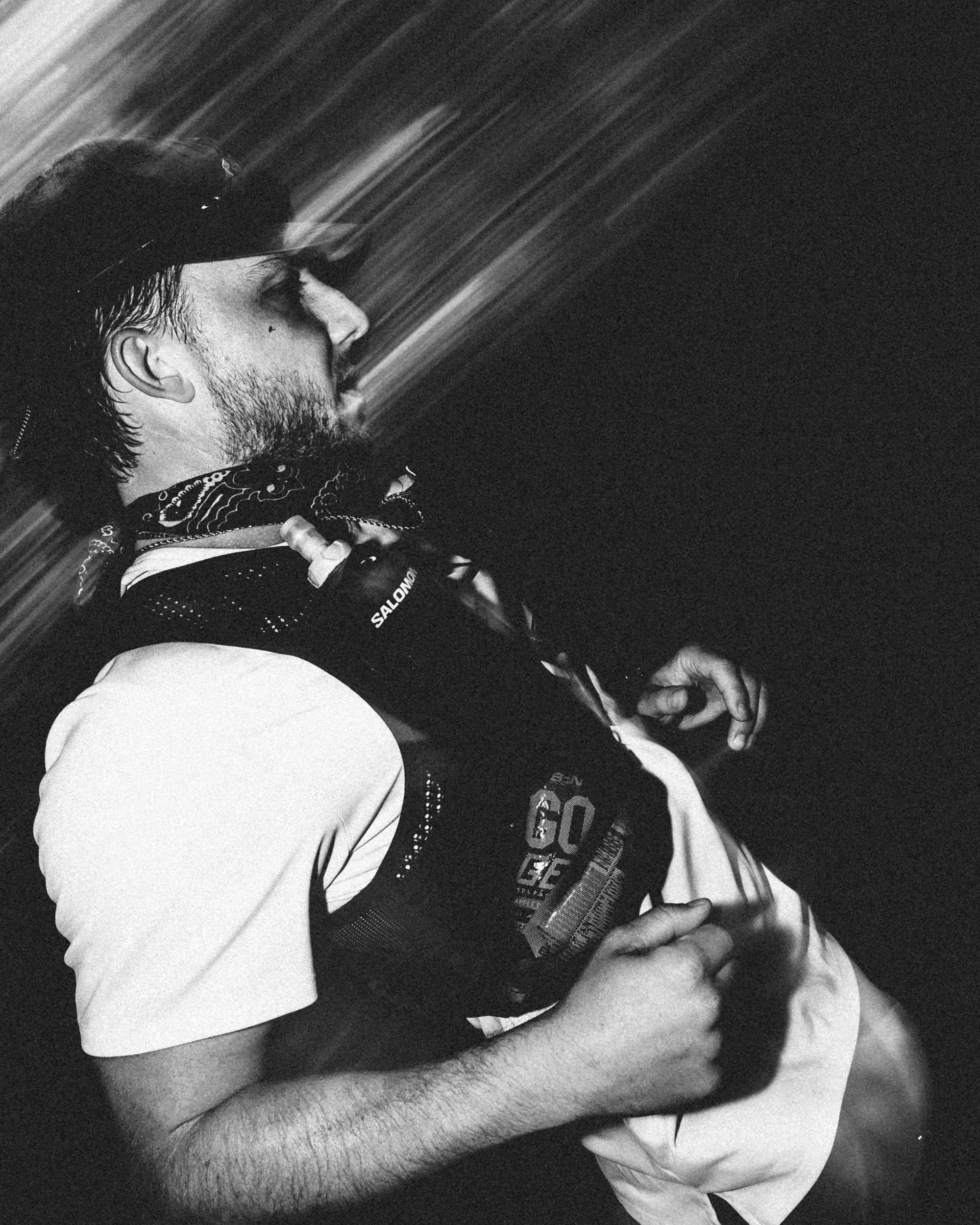 Black and white photo of a man with a beard and a hat kissing a person's forehead, with one of his hands on the person’s head.