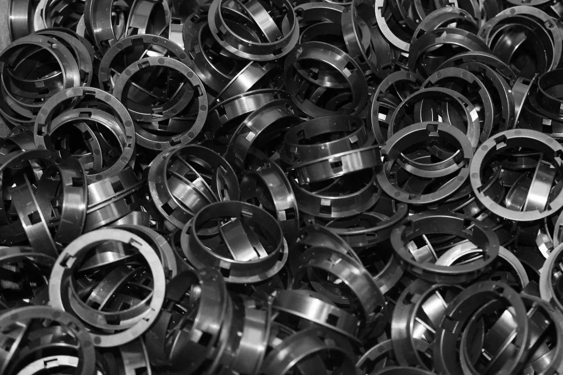A large pile of black metallic rings or washers, randomly stacked and overlapping each other.