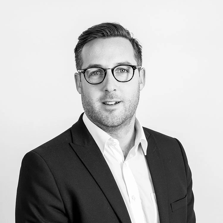 Black and white portrait of a man in a suit wearing glasses.