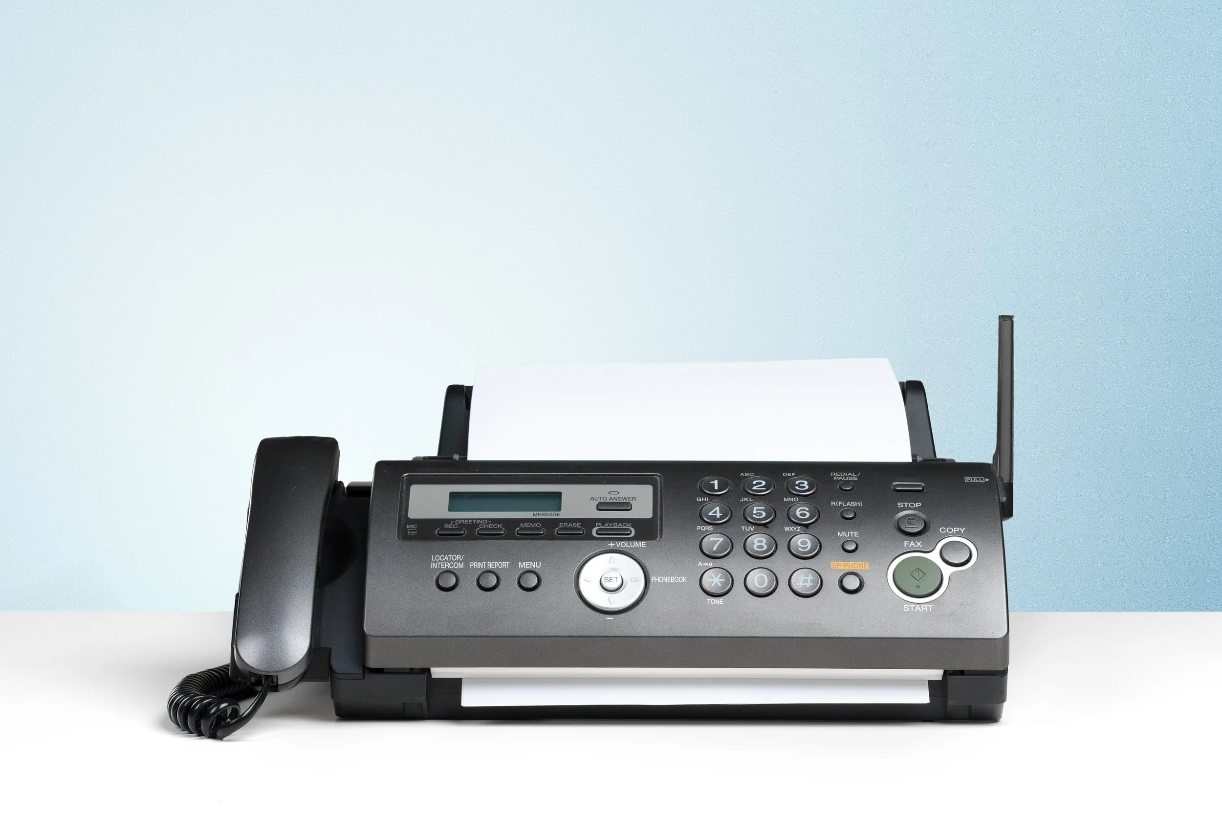 Multifunction office phone with a built-in fax machine and printer on a white desk
