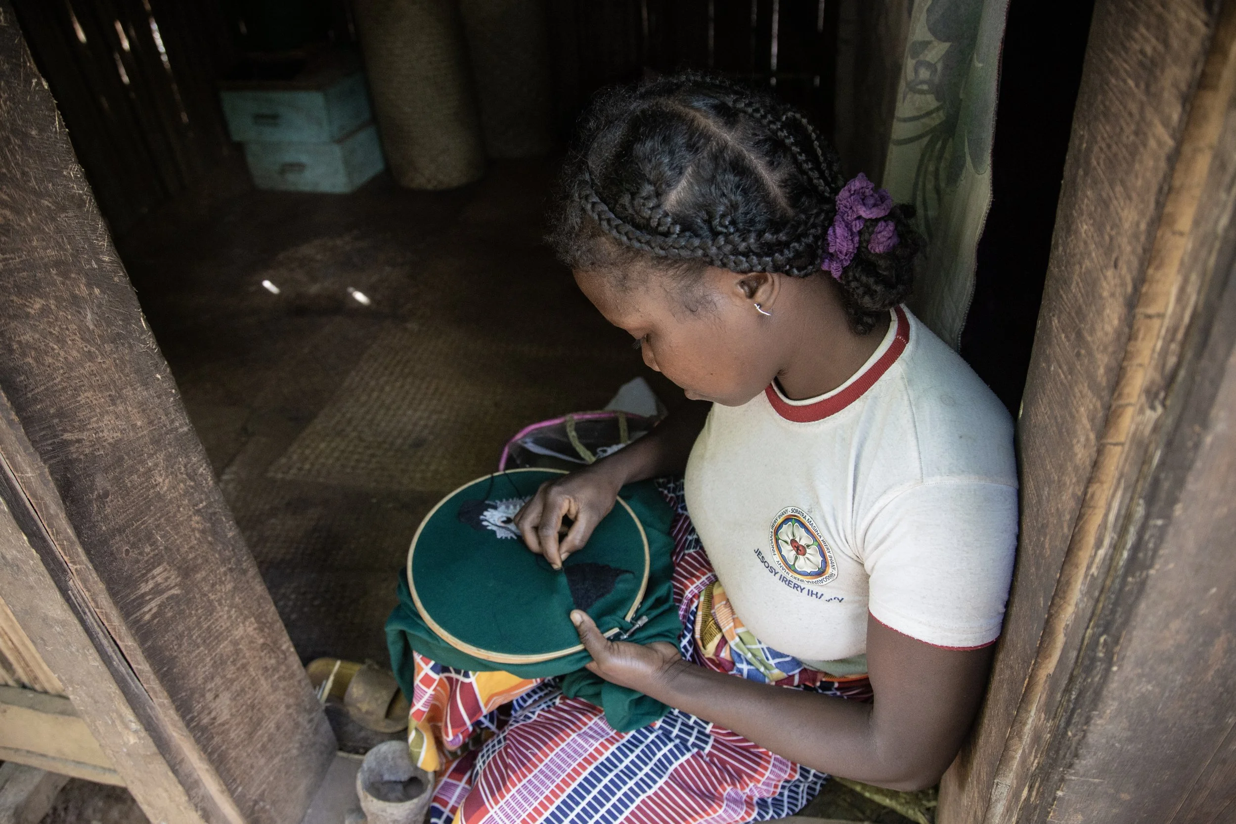 young woman embroidering in a Madagascar home, seen from above