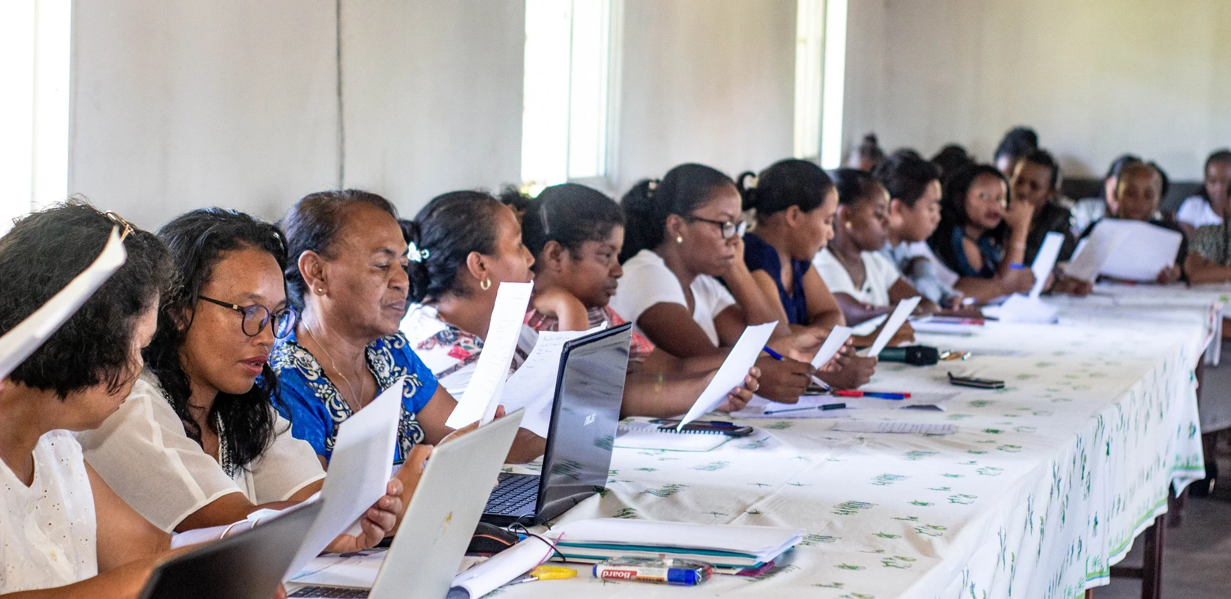 women in conference room during cervical cancer screening training, reading papers and looking at a computer
