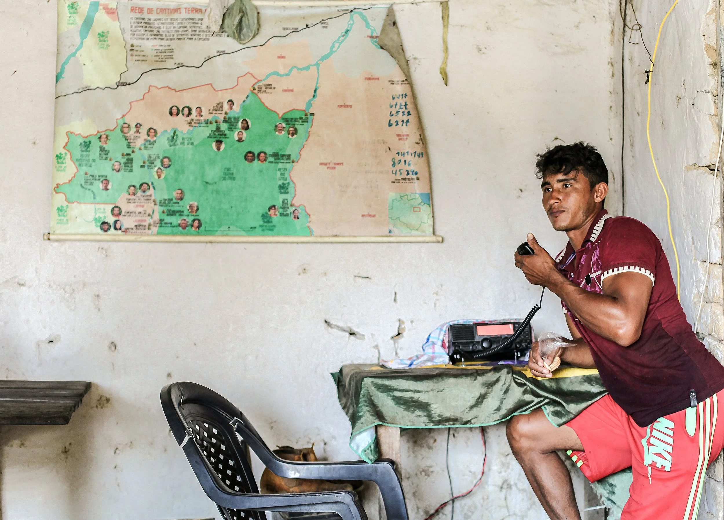 man speaking on a ham radio near a map of the Amazon rainforest