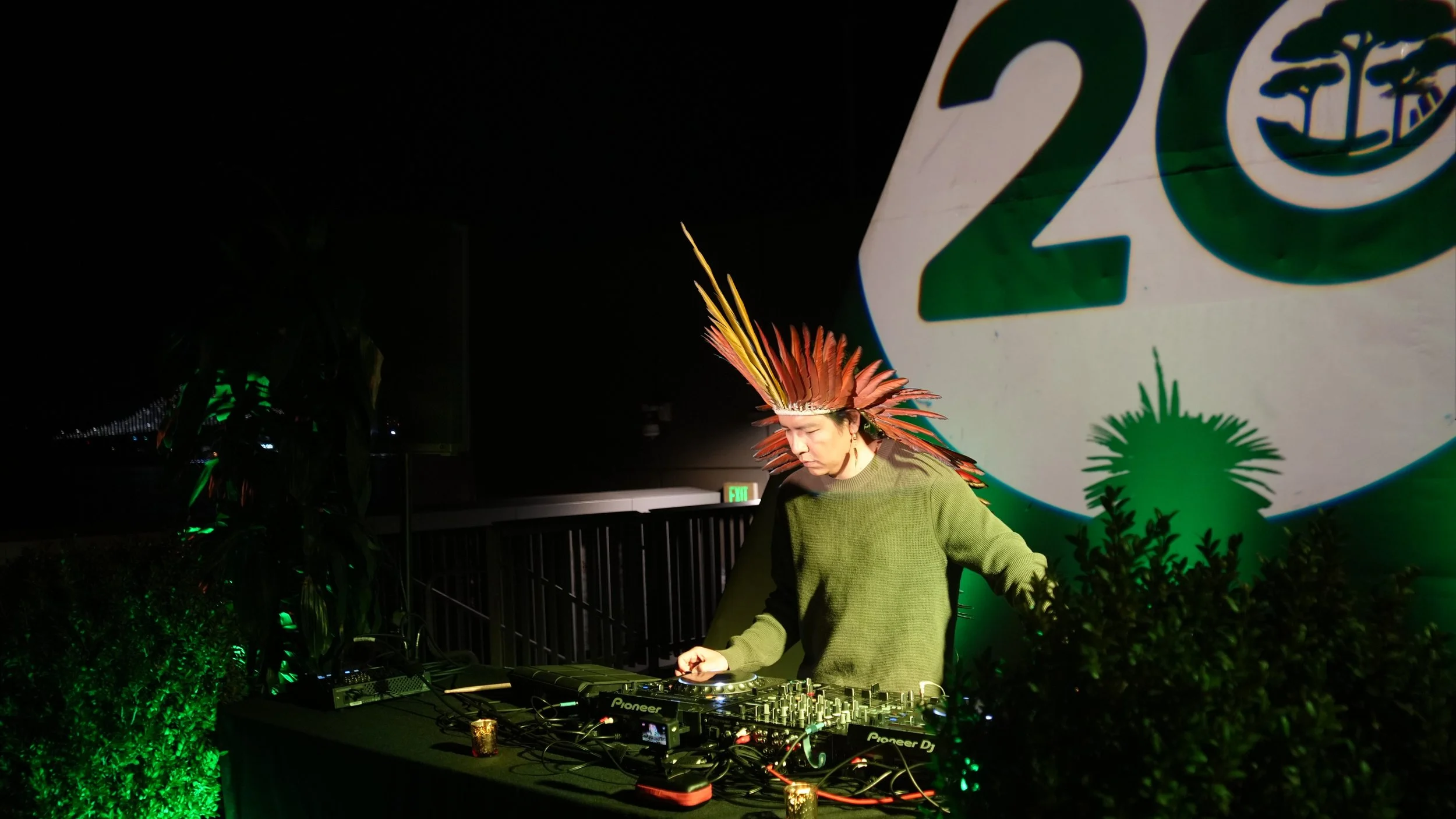 DJ Eric Terena performs in front of a spotlight projecting the Health In Harmony logo