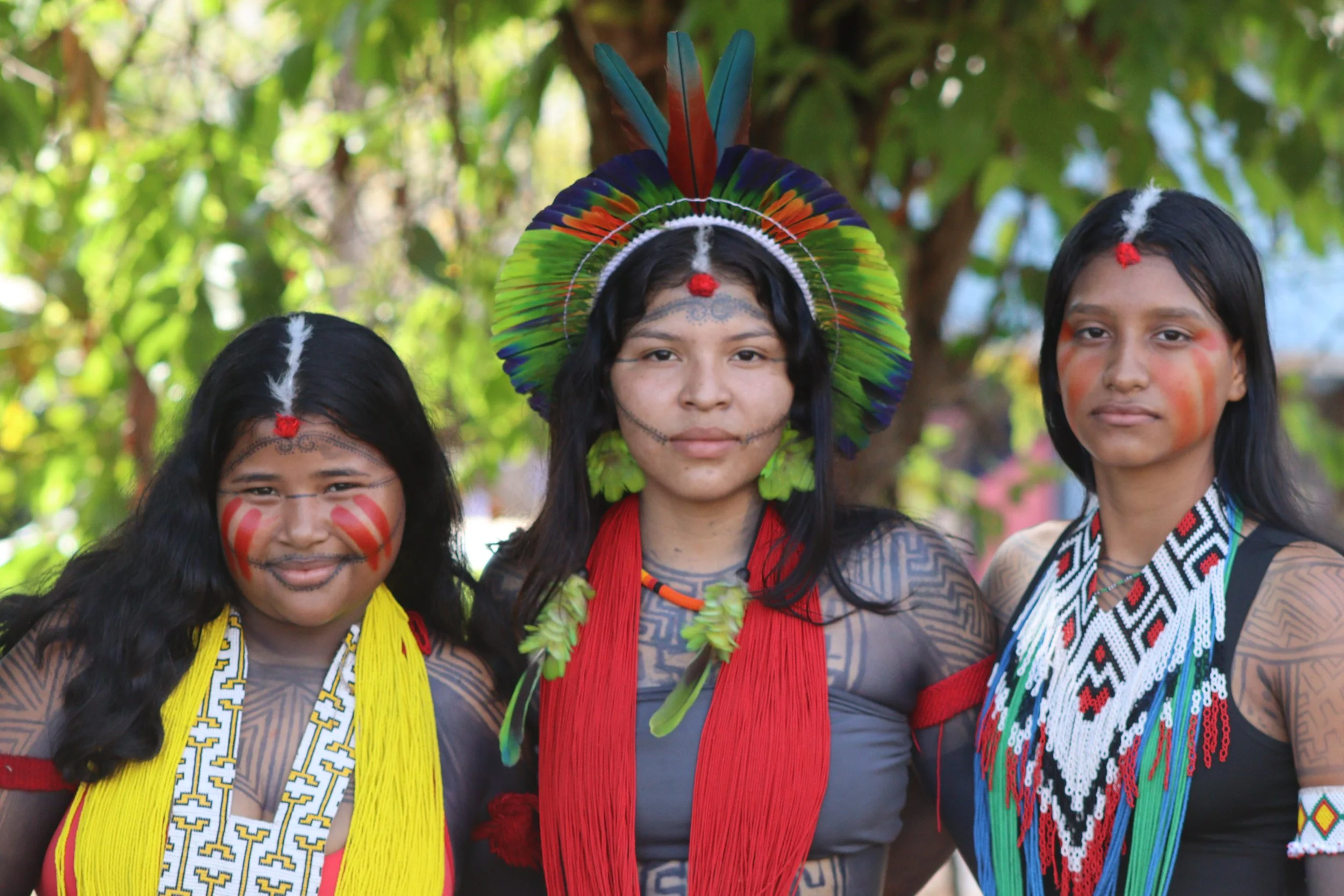 three young Indigenous women pose for a photo in the Xipaya community, Brazilian Amazon