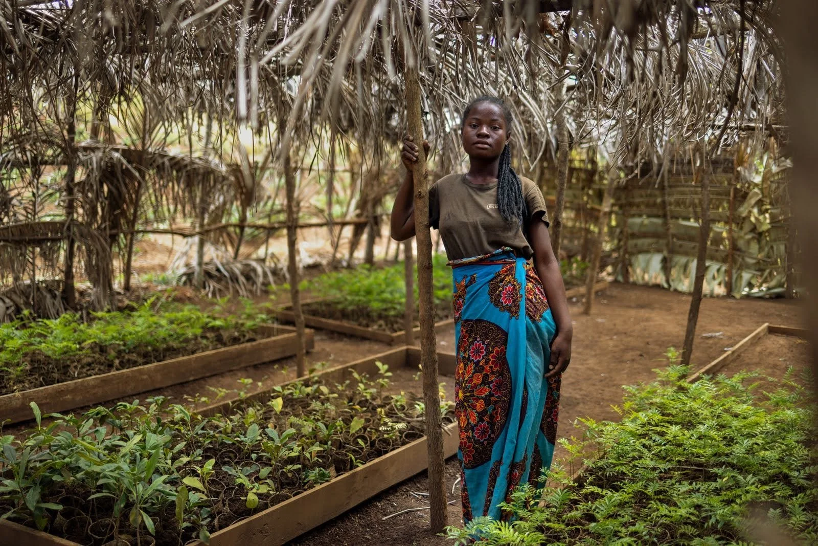 woman stands in a tree nursery in Madagascar, facing camera