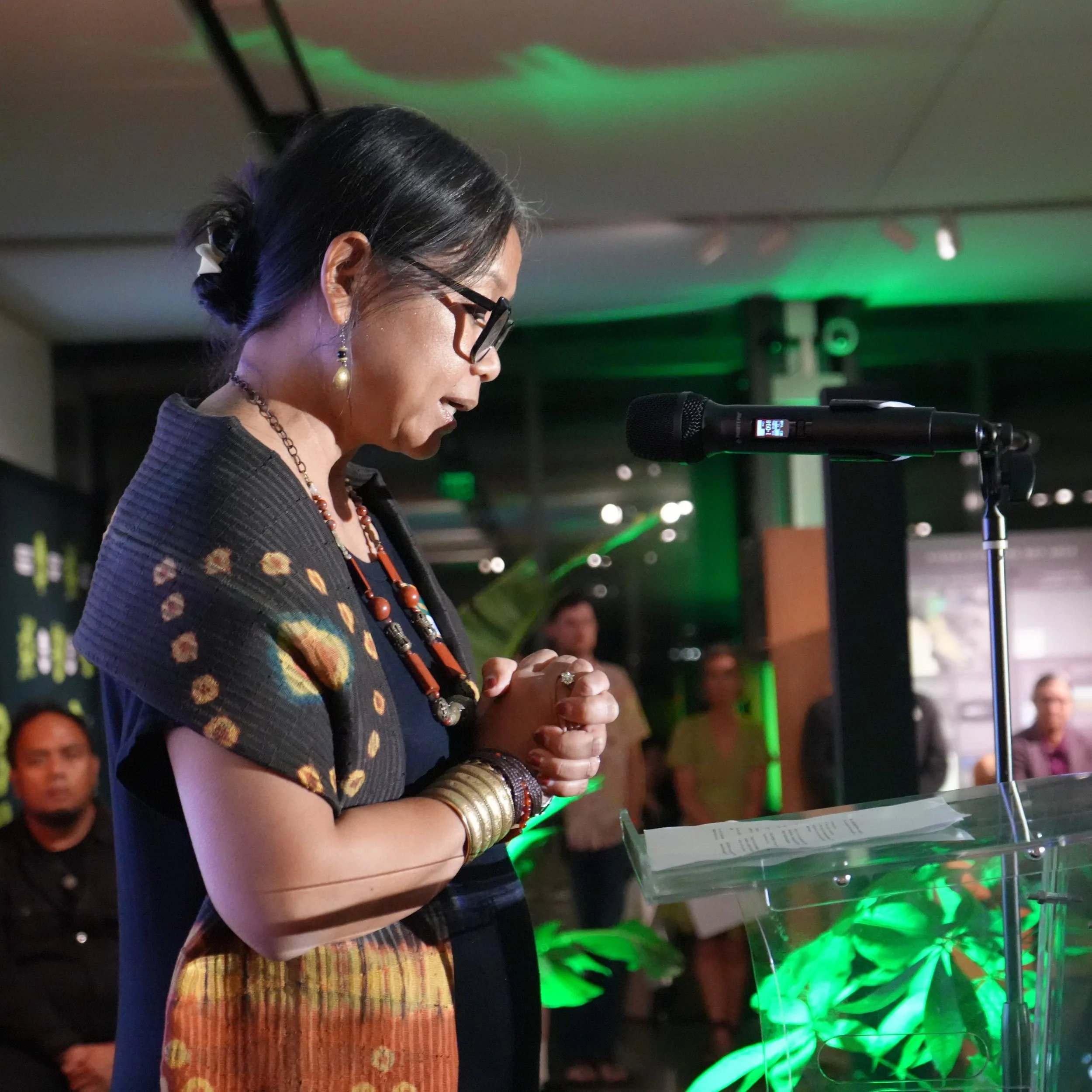 Yani Saloh, seen from the side, speaks on the stage