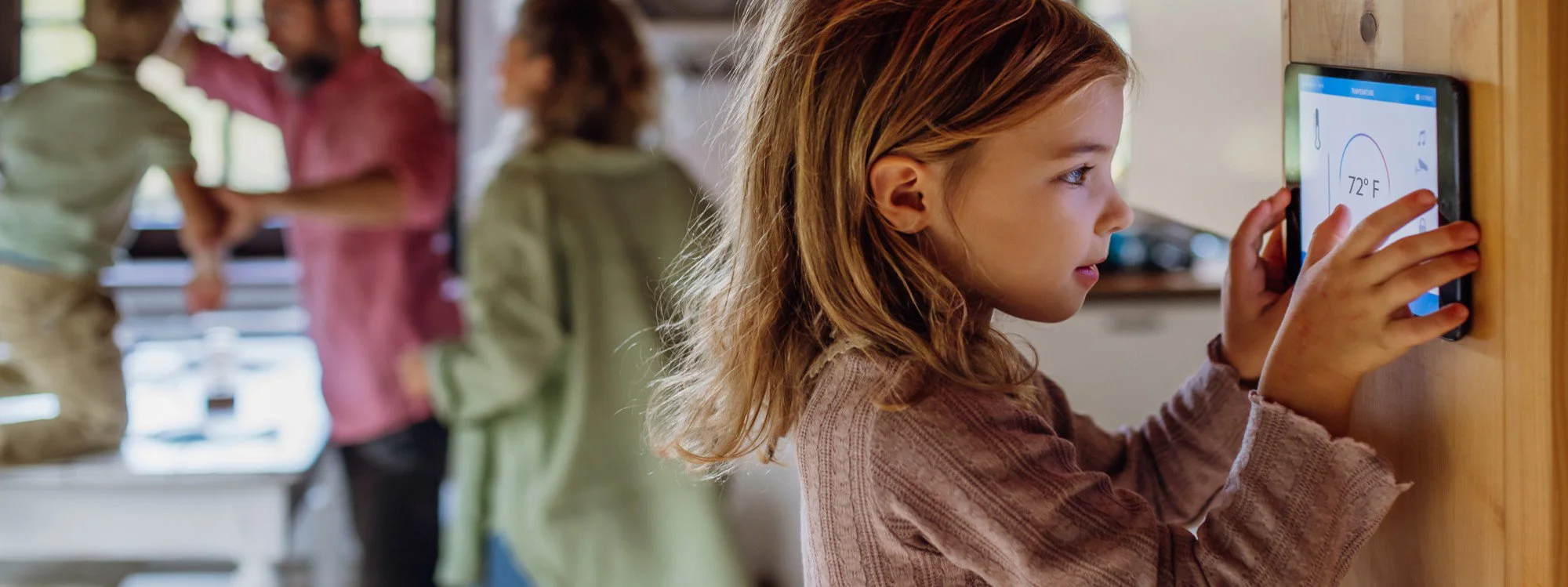 Young girl with red hair adjusting a thermostat in a kitchen, enjoying home comfort with FT Young HVAC in Bucks County, PA
