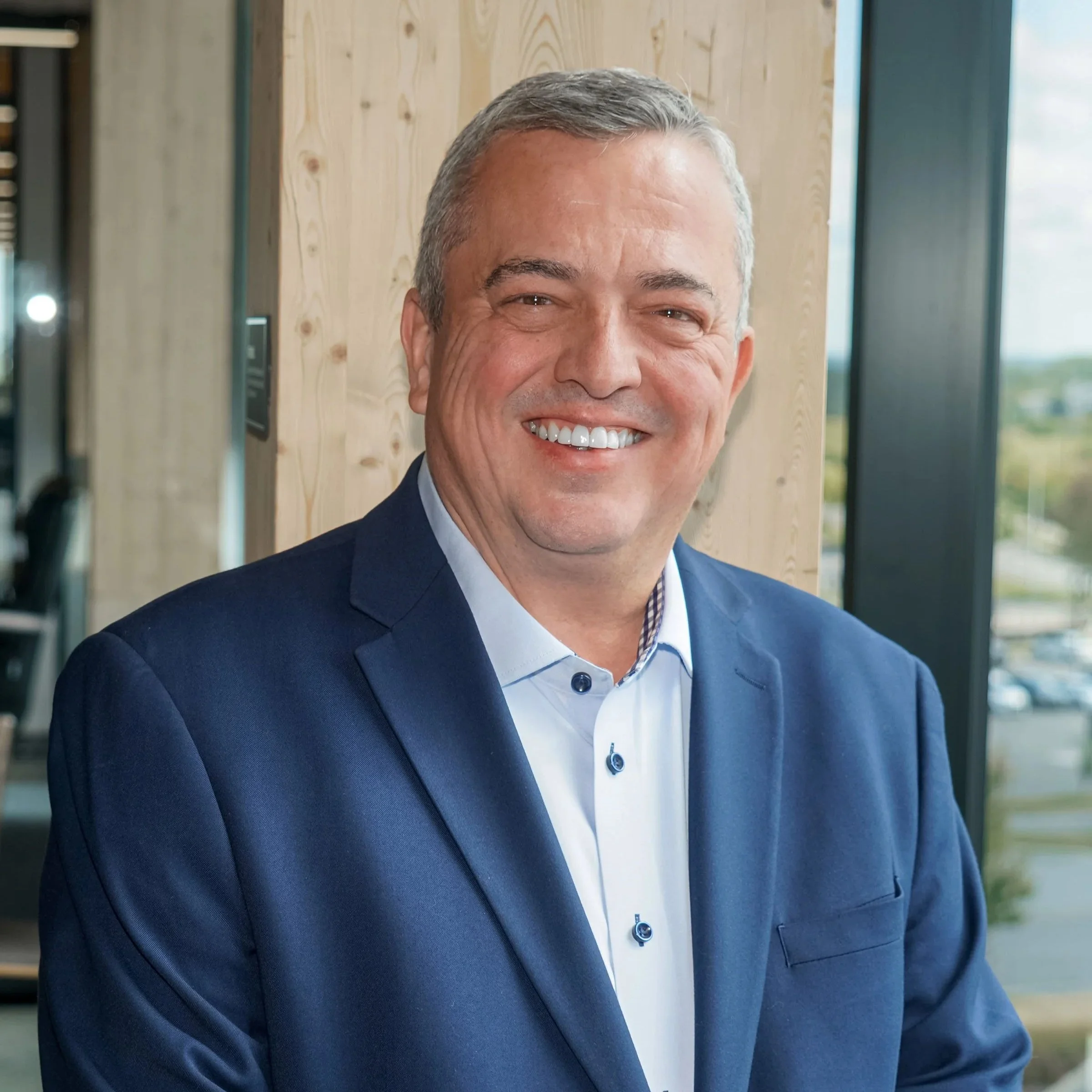 Portrait d'un homme d'affaires souriant en costume, en intérieur.