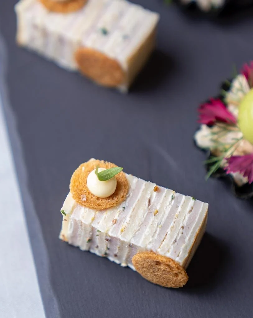 Gourmet appetizer resembling a car with cream cheese, crackers, and herbs on a slate plate.