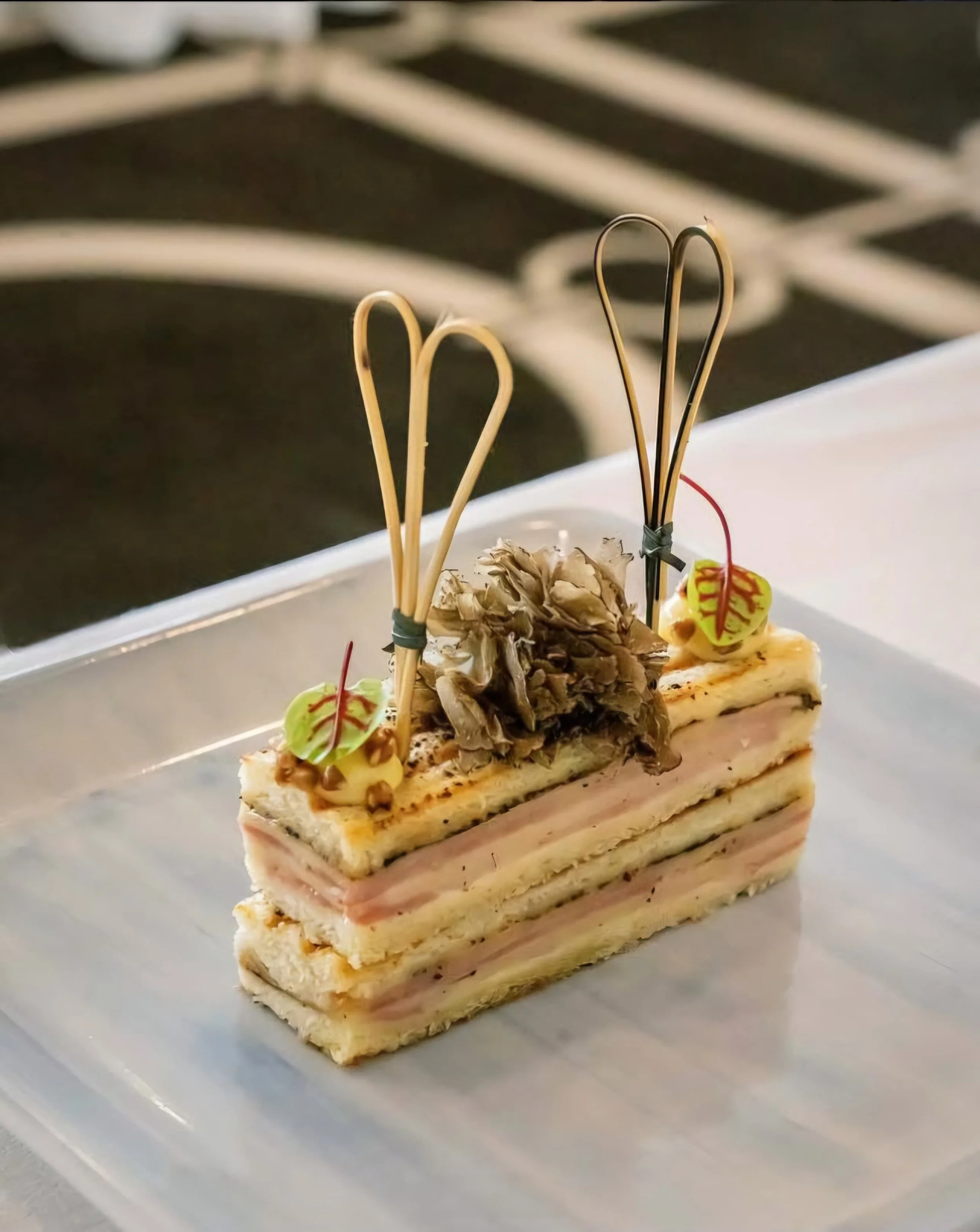 Layered sandwich with skewers and garnishes on a plate