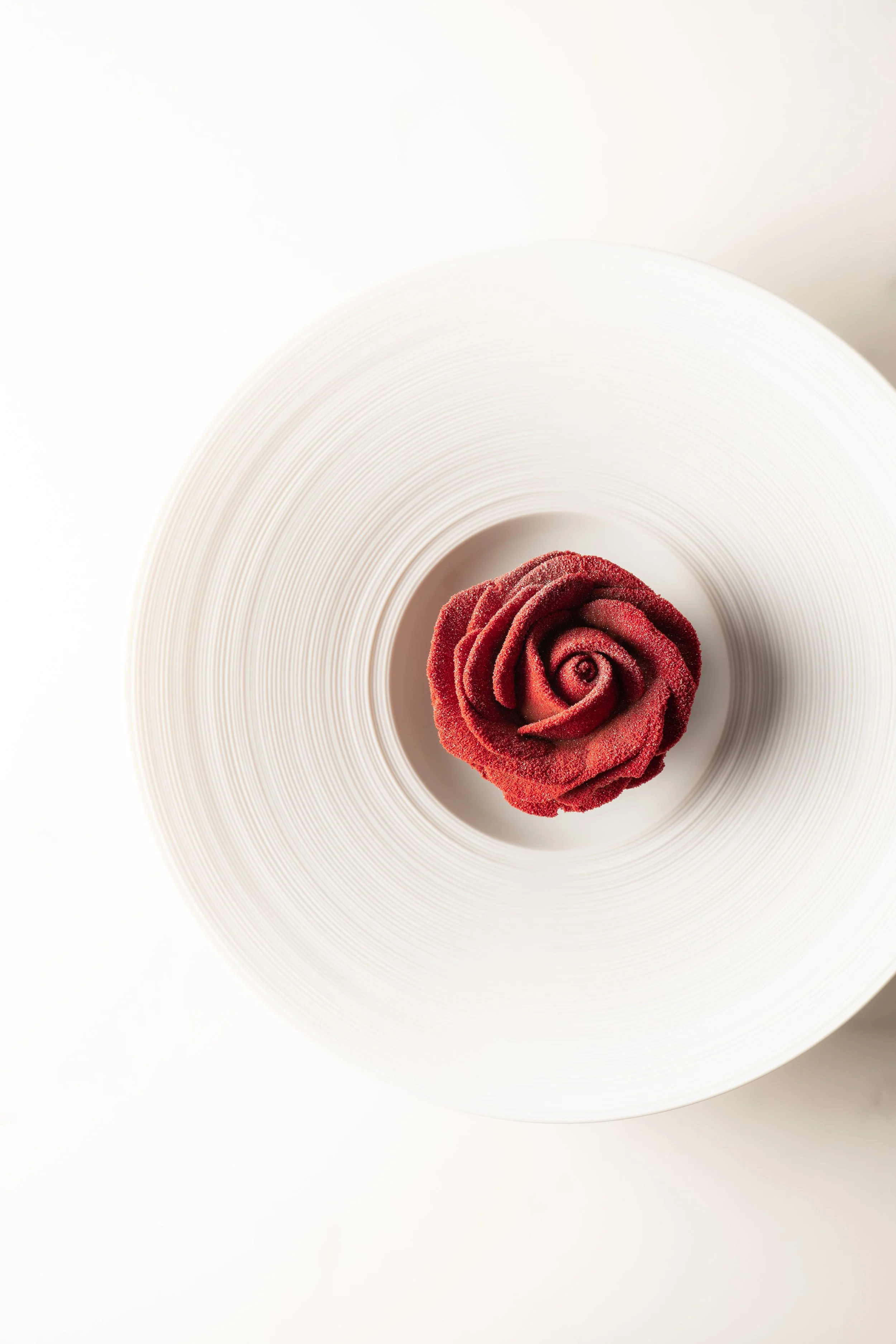 Red rose-shaped dessert on a white textured plate