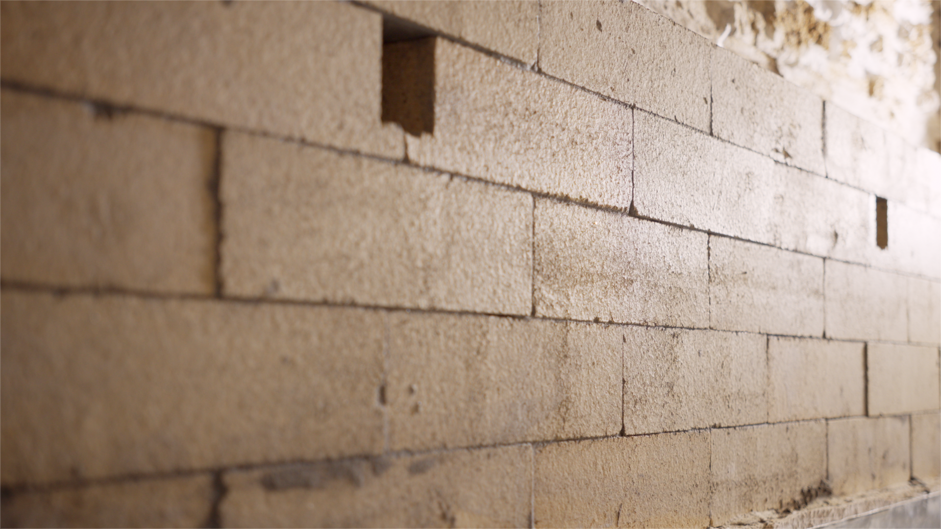 Close-up of a beige brick wall with evenly laid rectangular bricks and mortar lines.