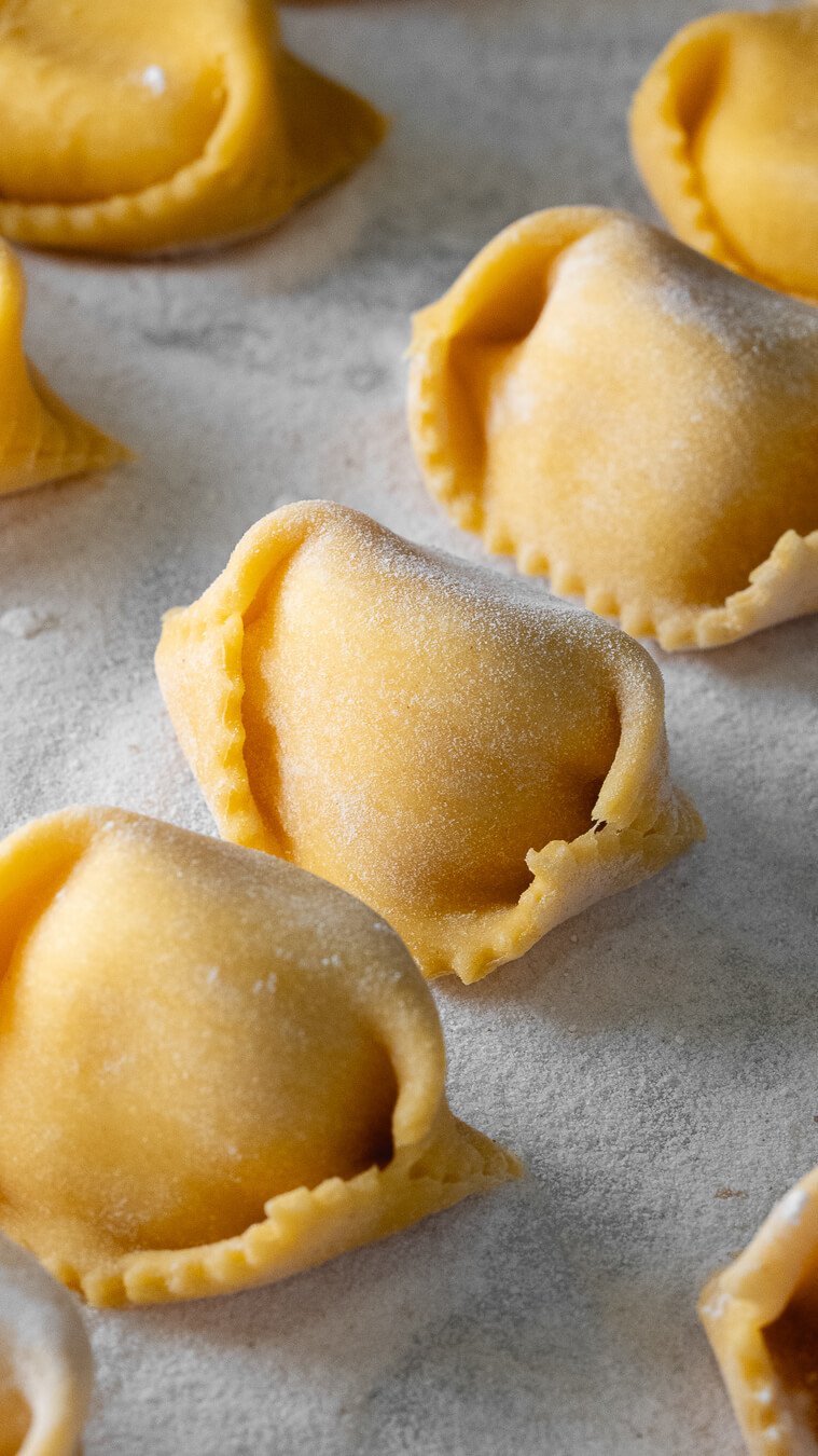 Raw fresh tortellini pasta arranged on a baking sheet