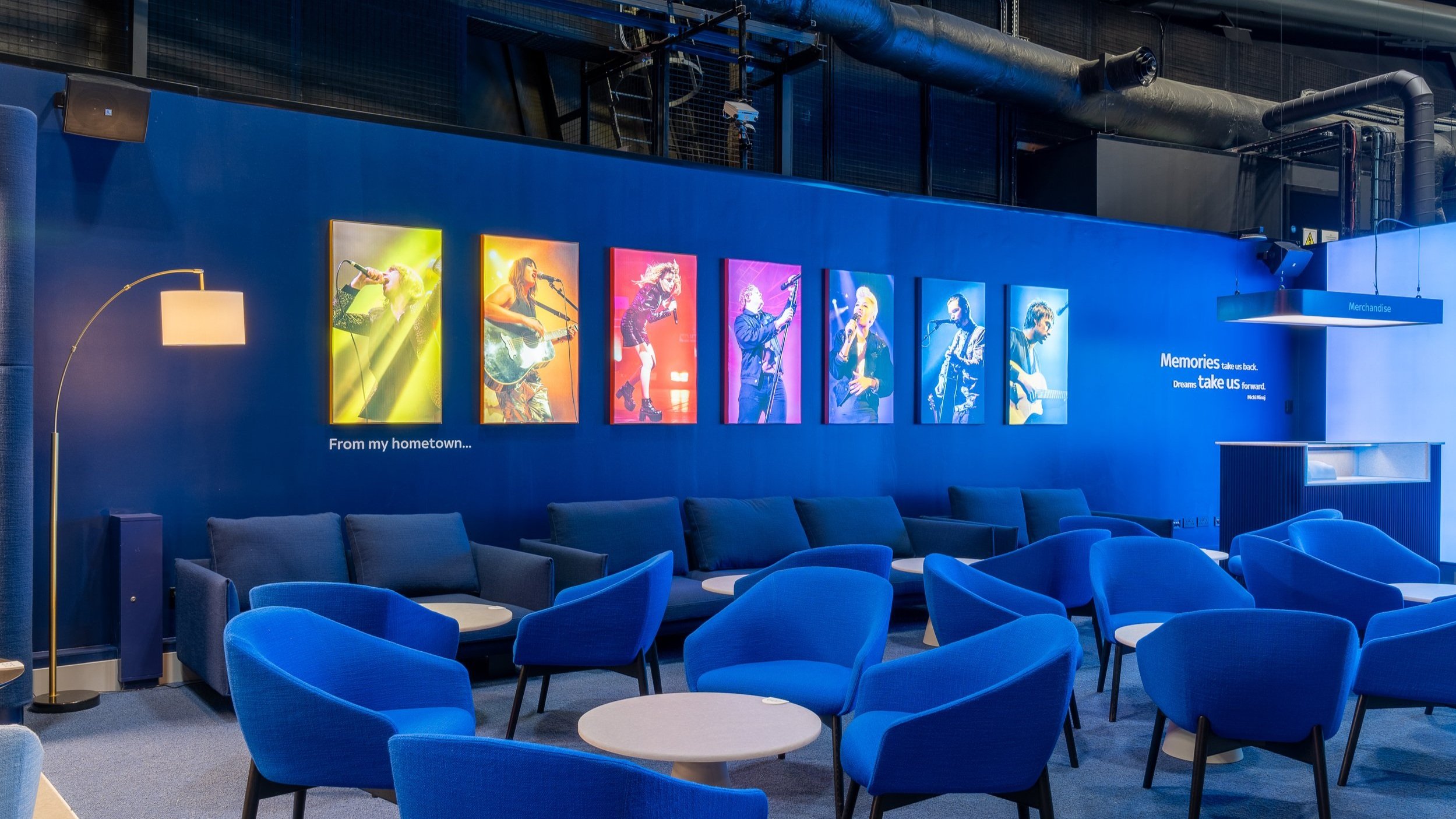 Interior of a modern lounge or waiting area with framed colorful photos of musicians, blue chairs, and inspirational wall text, photographed by an interior photographer Scotland.