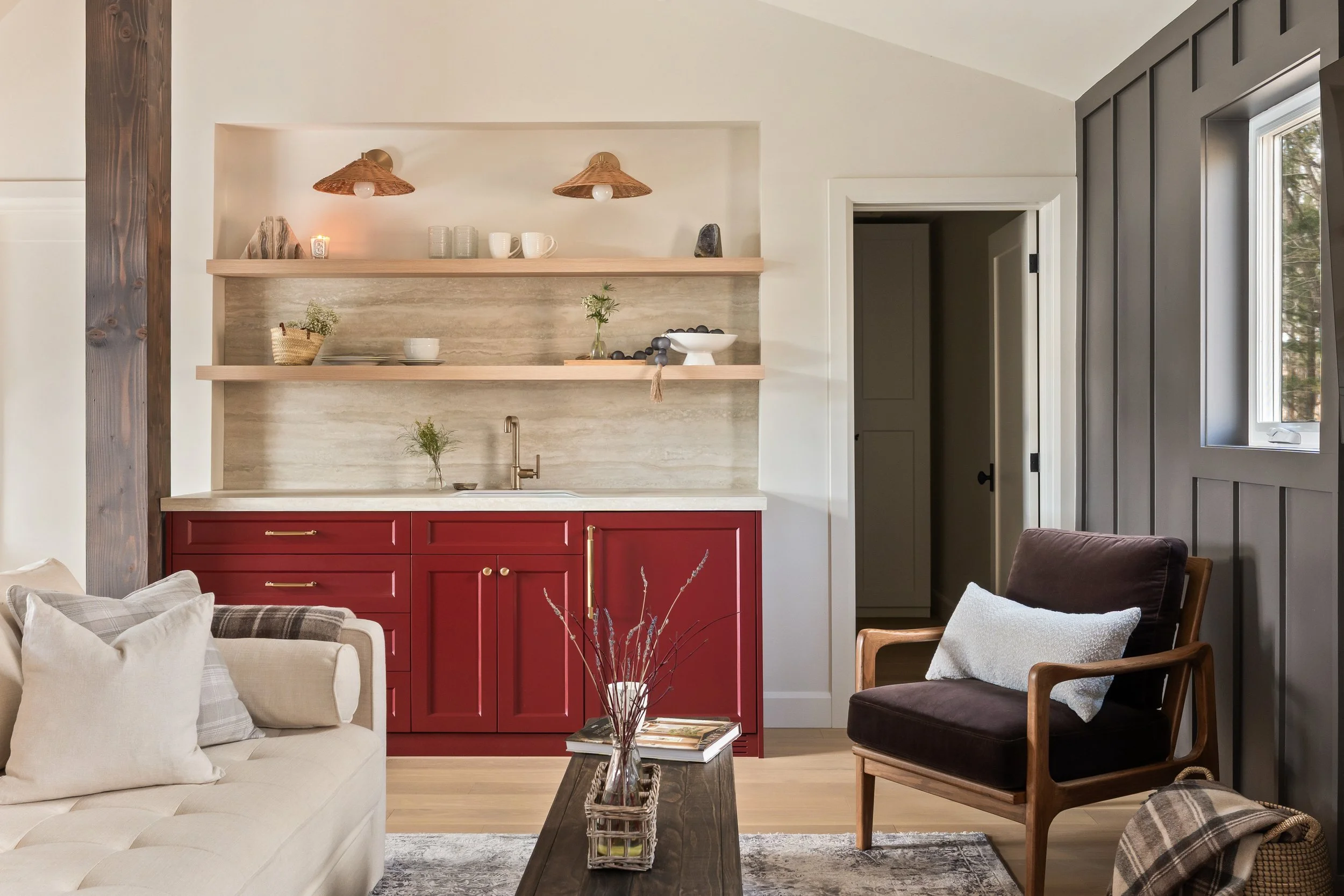 Wet bar with red cabinetry and travertine countertop by Pearl Kitchens