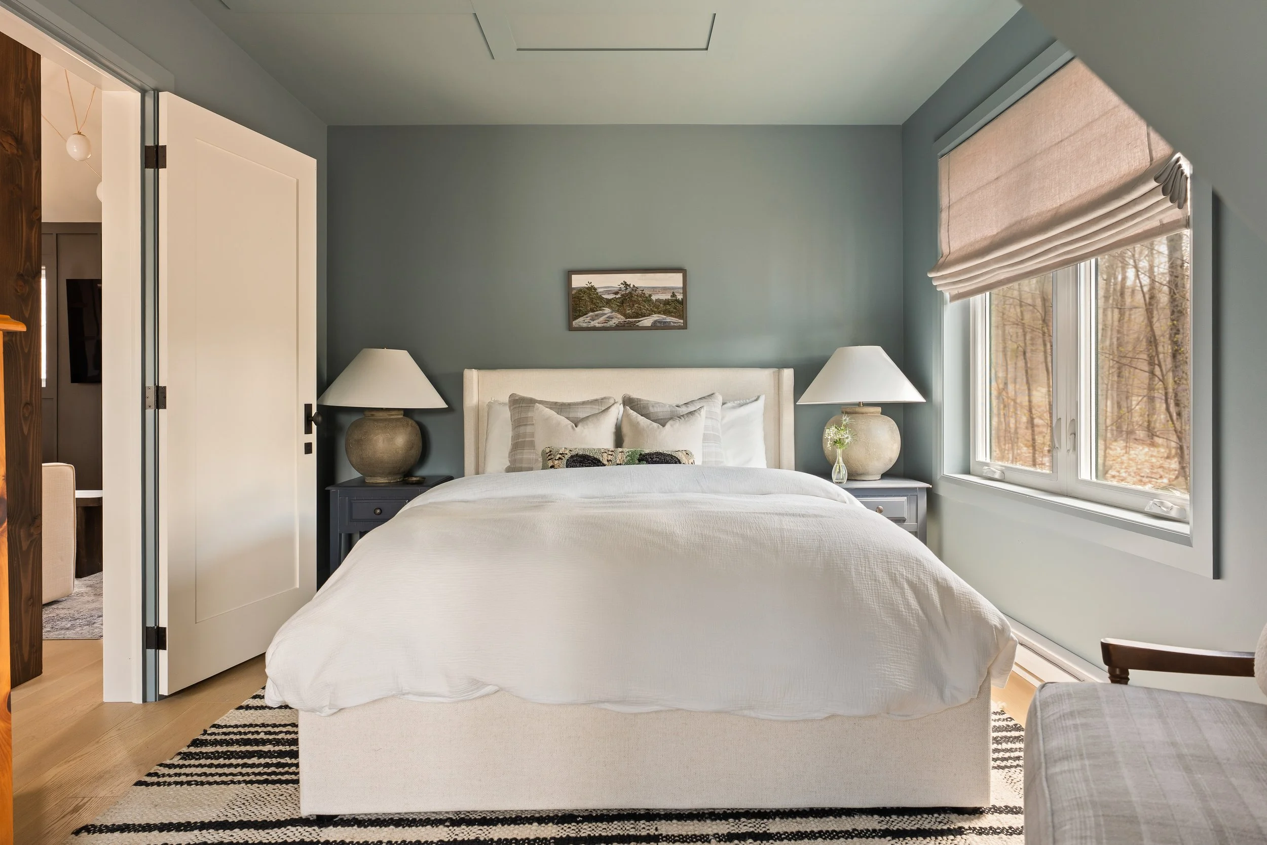 Guest bedroom in soft blue palette with hand-painted antique nightstands