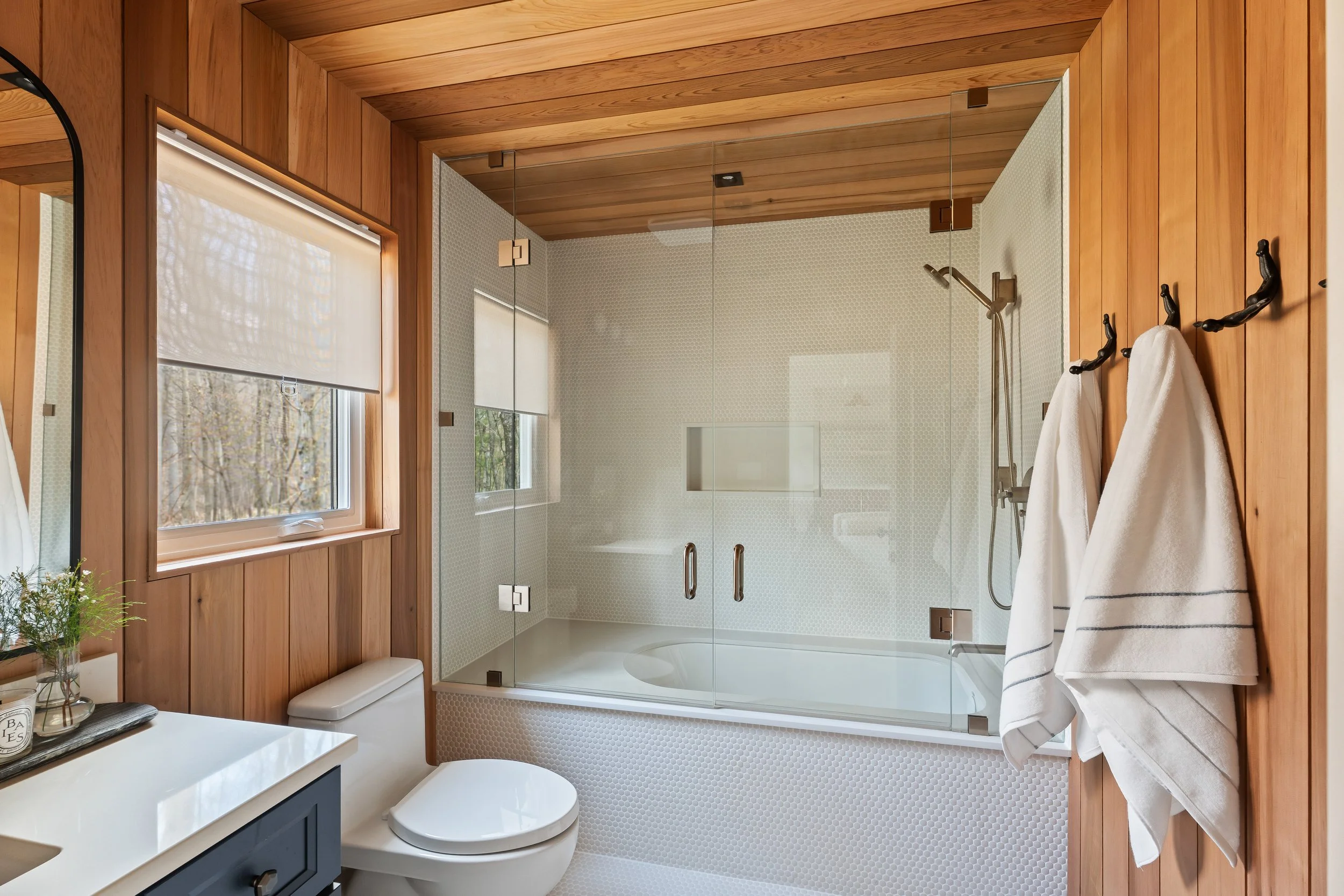 Spa-inspired bathroom with cedar walls and penny tile flooring