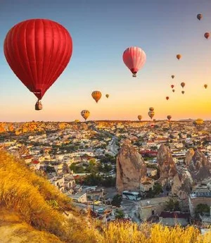 Hot air balloons rising over a valley at sunrise