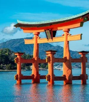 A vermilion torii gate standing in shallow sea water