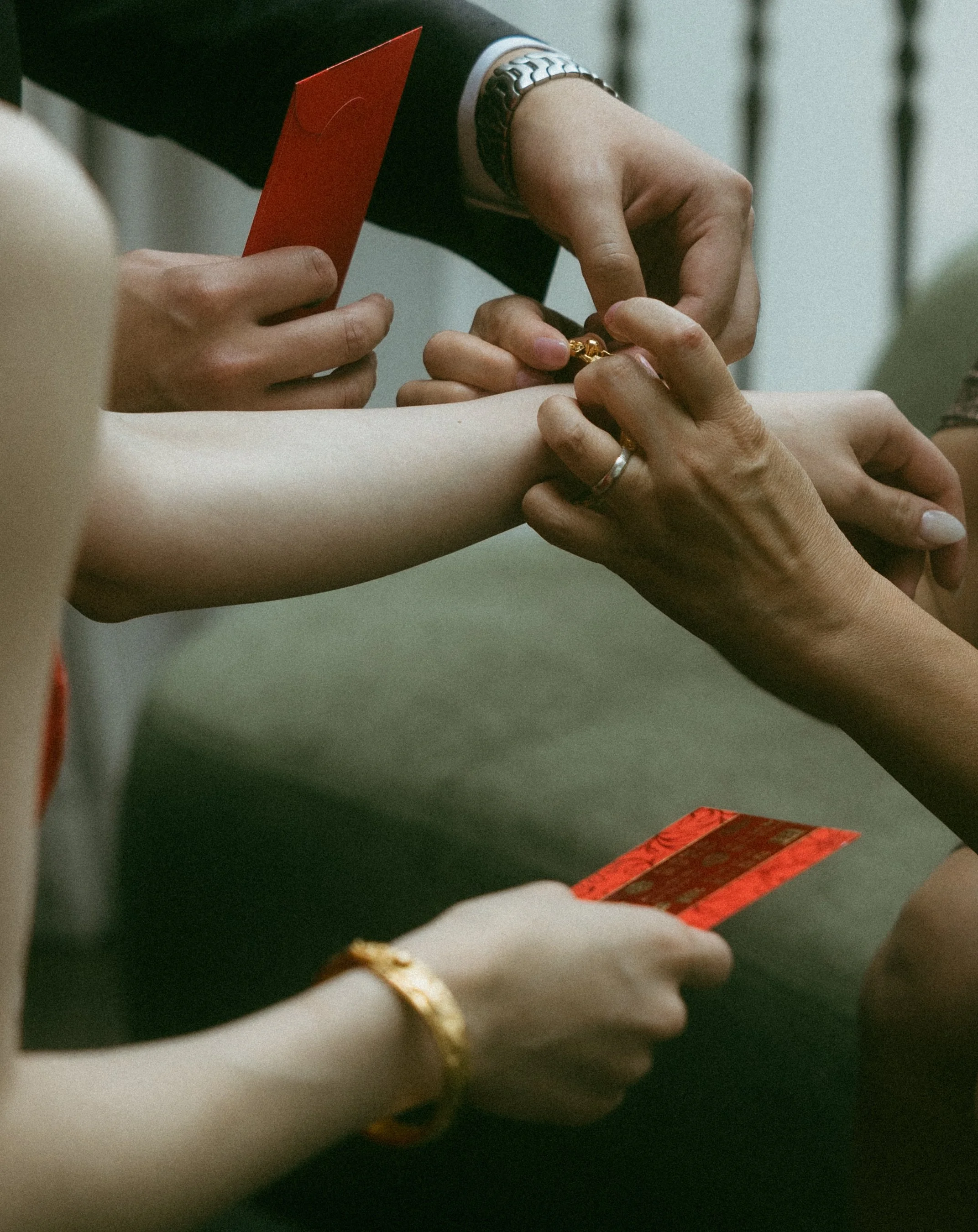 Several hands exchanging red envelopes at a formal event.