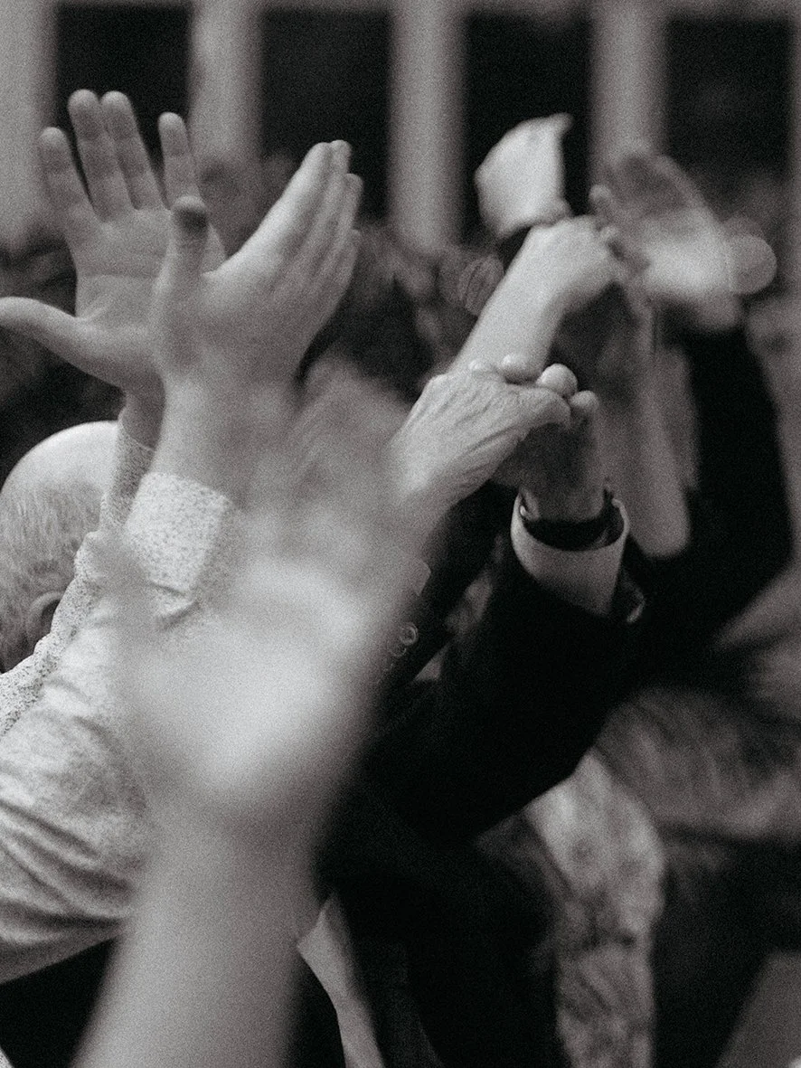Close-up of people's hands clapping, with some hands holding phones, in black and white.
