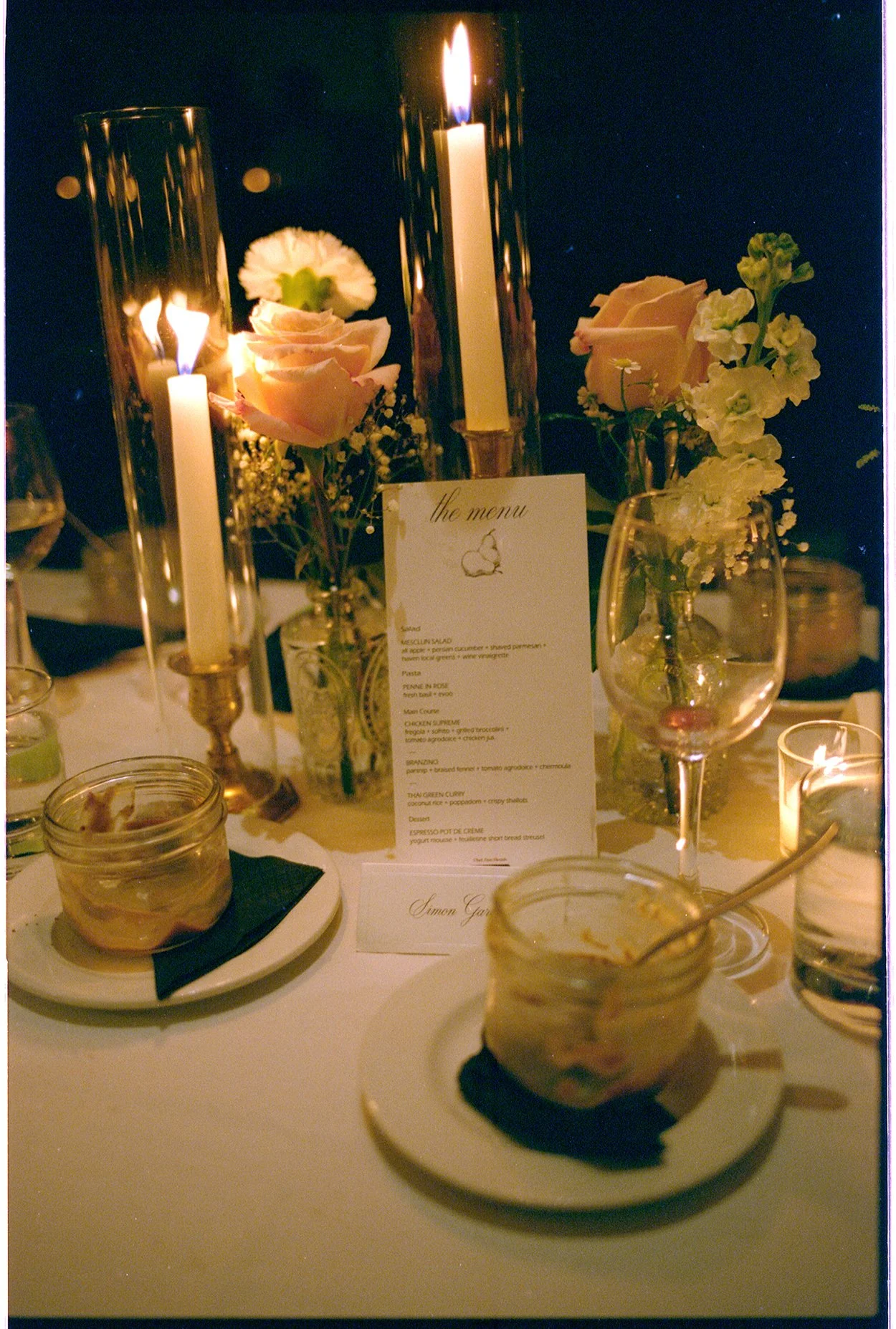 Table decorated with candles, flowers, and a menu card at a dinner event.