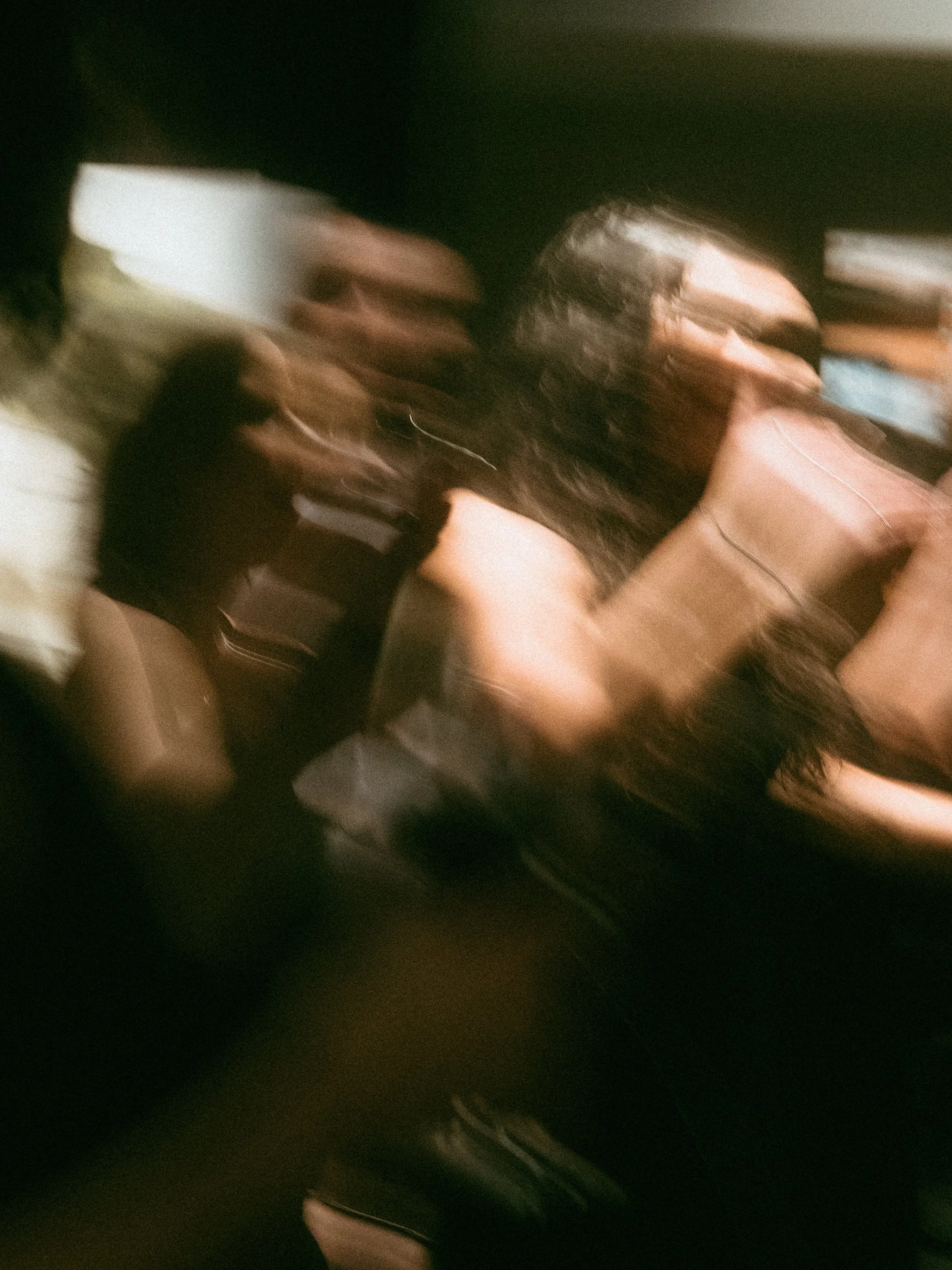 Blurry photo of two women sitting in a car, one with long dark hair and the other with glasses and curly hair, using a smartphone.