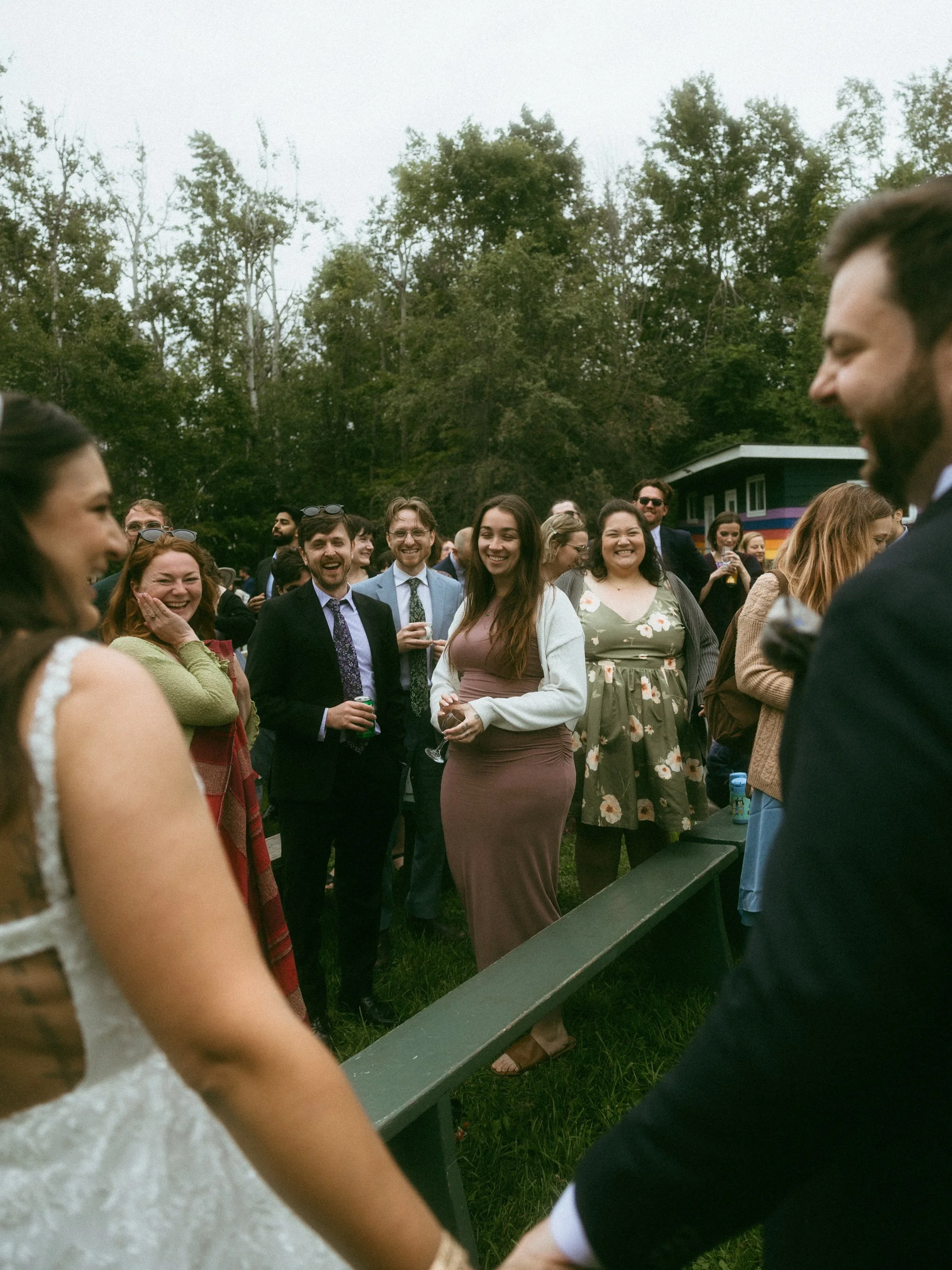 A group of people dressed in formal attire at an outdoor wedding reception, smiling and enjoying each other's company.