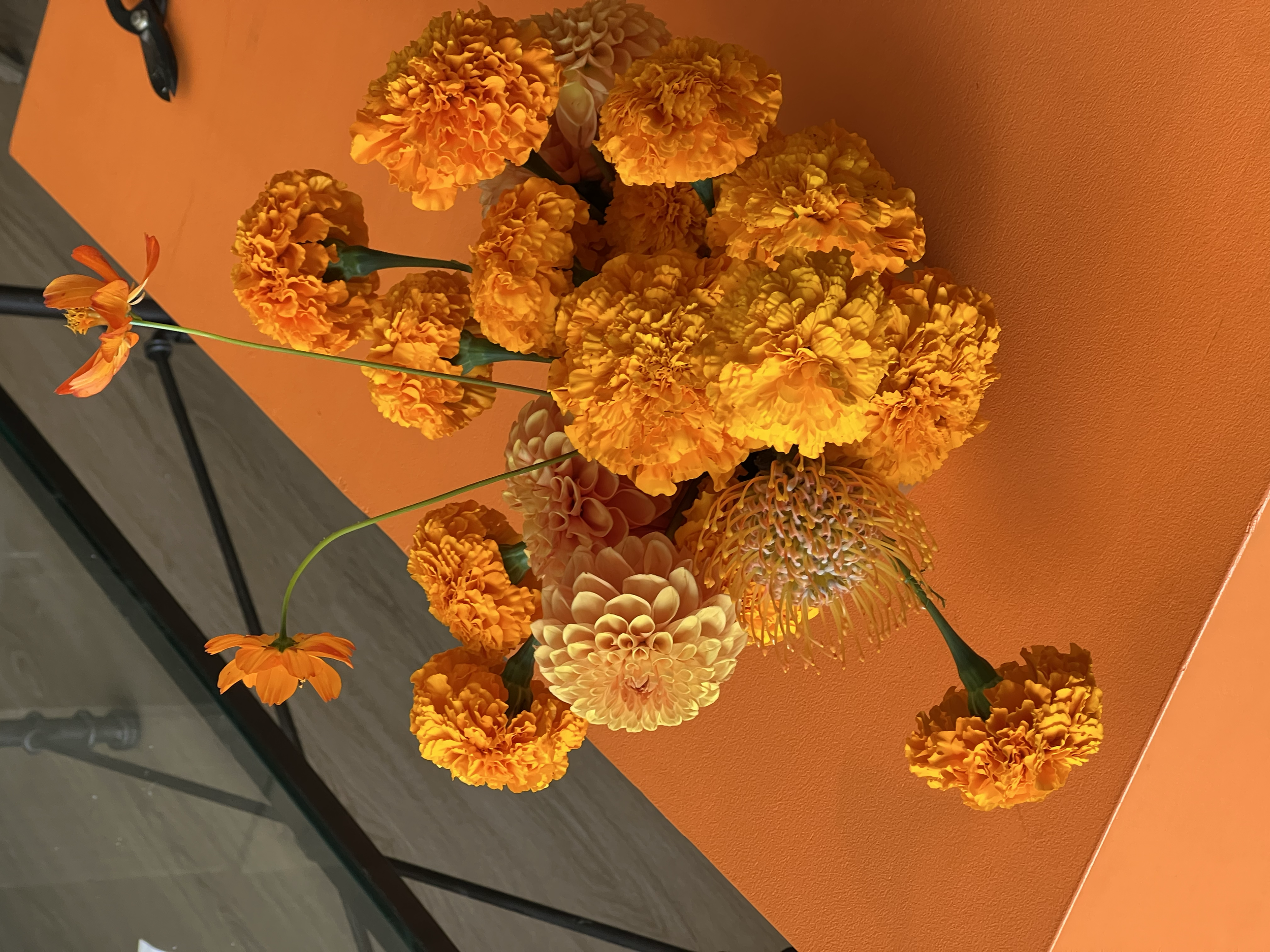A bouquet of yellow and orange marigold flowers placed on an orange table.