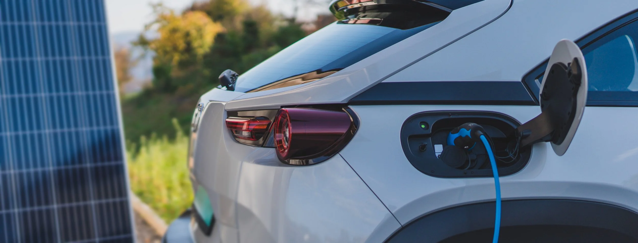 A photo of an electric vehicle (EV) charging station installed in a garage by an electrical company in Cle Elum, WA. The charging plug is connected to a Tesla vehicle, which is parked inside the garage. The wall-mounted EV charger is neatly installed