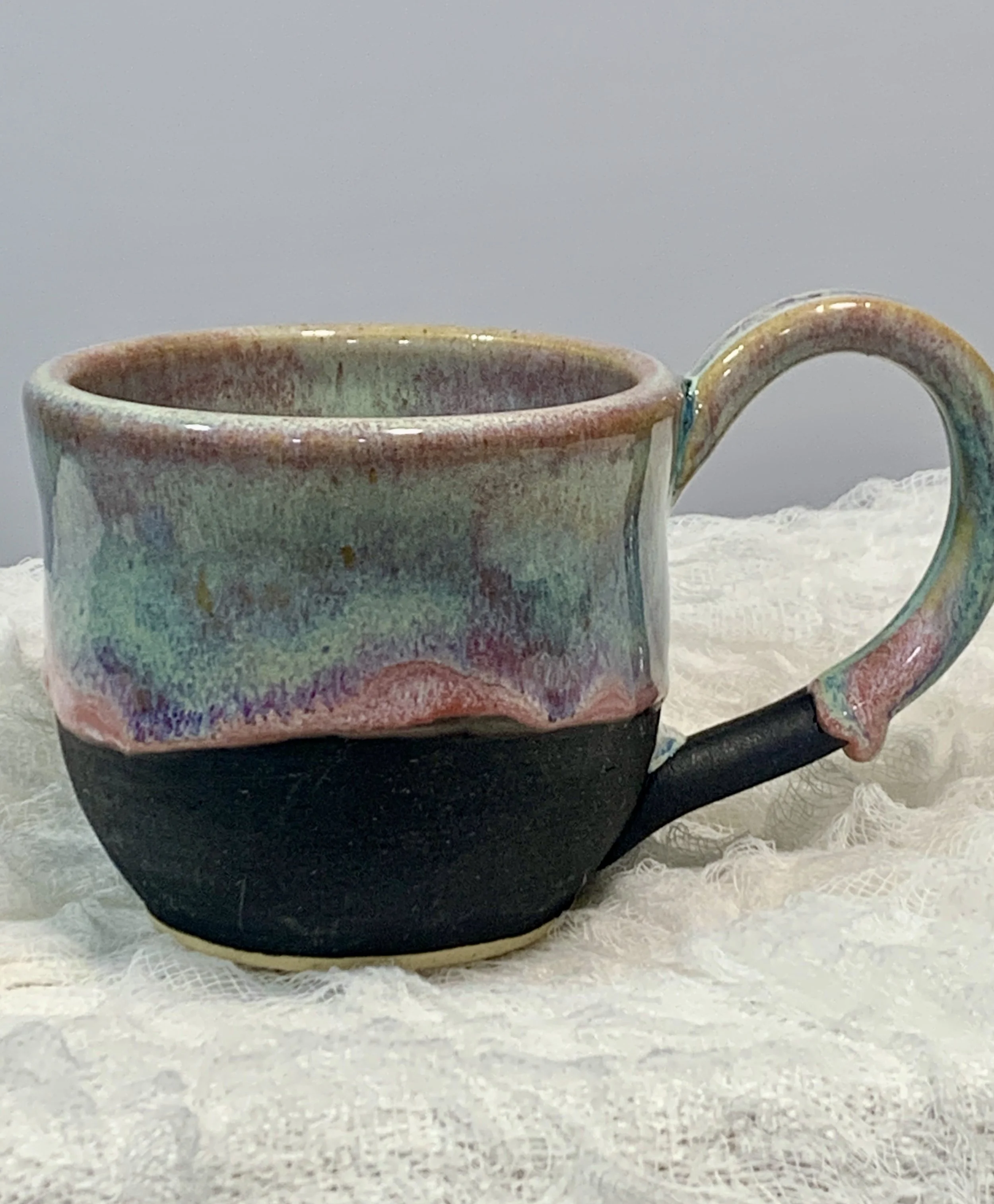 Handmade ceramic mug with a blue glaze and floral design