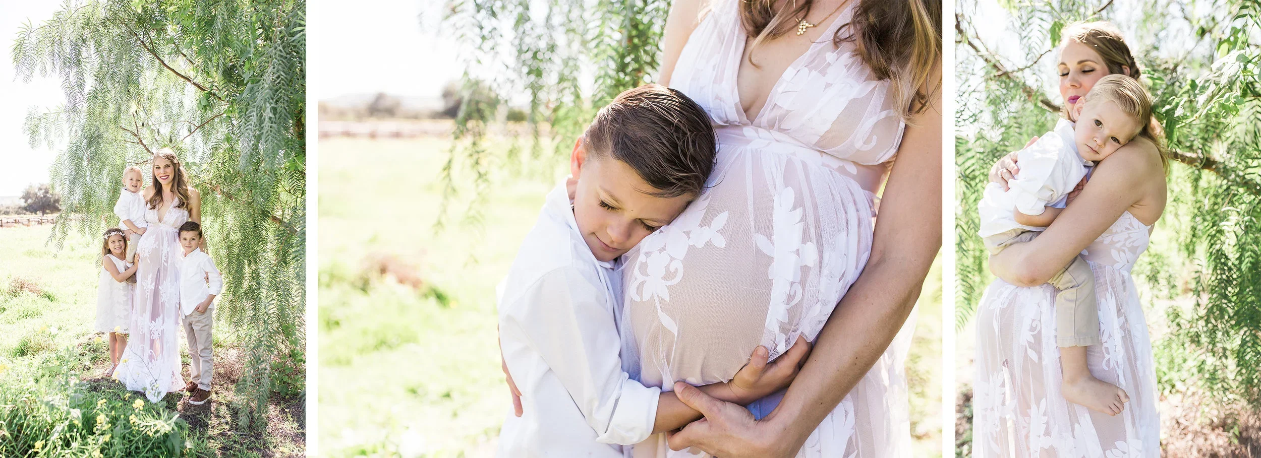 A woman and three children outdoors near trees. The woman, wearing a light-colored dress, is holding a young boy hugging her pregnant belly. The boy is dressed in a white shirt and khaki pants. Two other children, a girl and a boy, are standing nearby, smiling at the camera, all dressed in white and light colors.