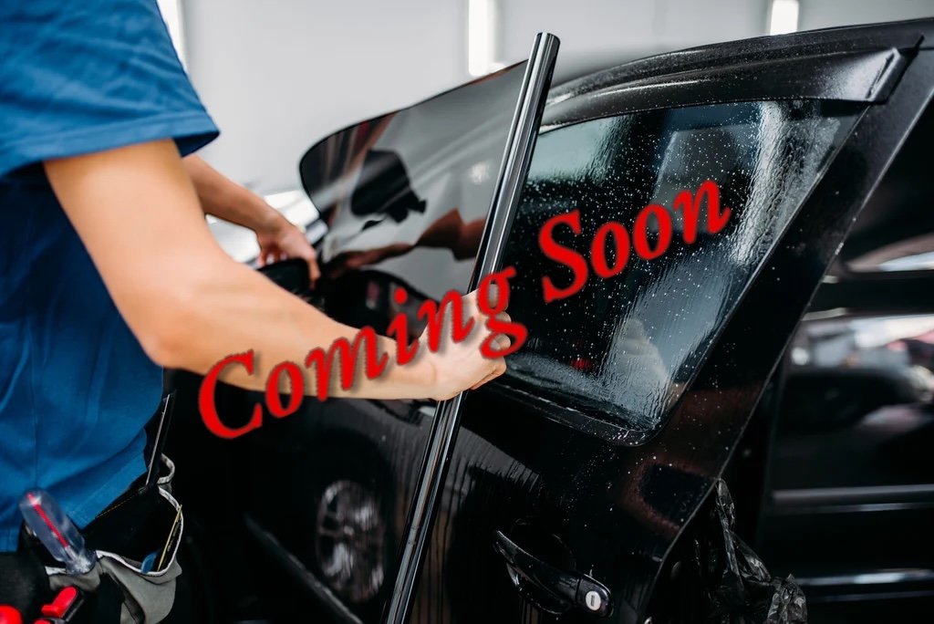 Person applying tint to car window with "Coming Soon" text overlay.