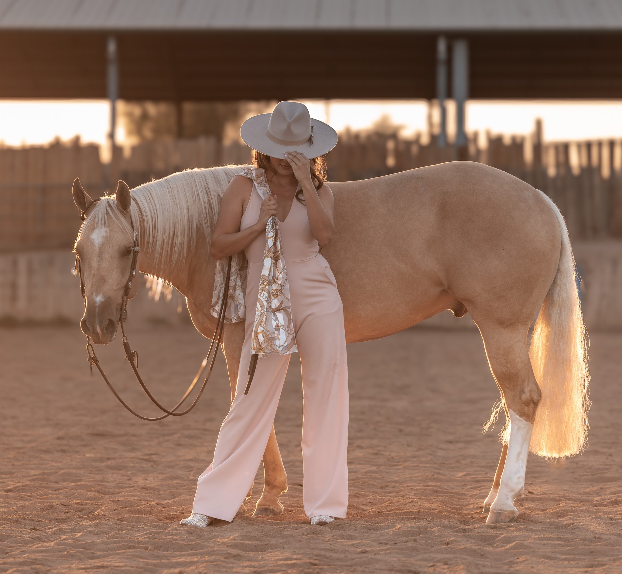 Woman in pink jumpsuit with palomino horse