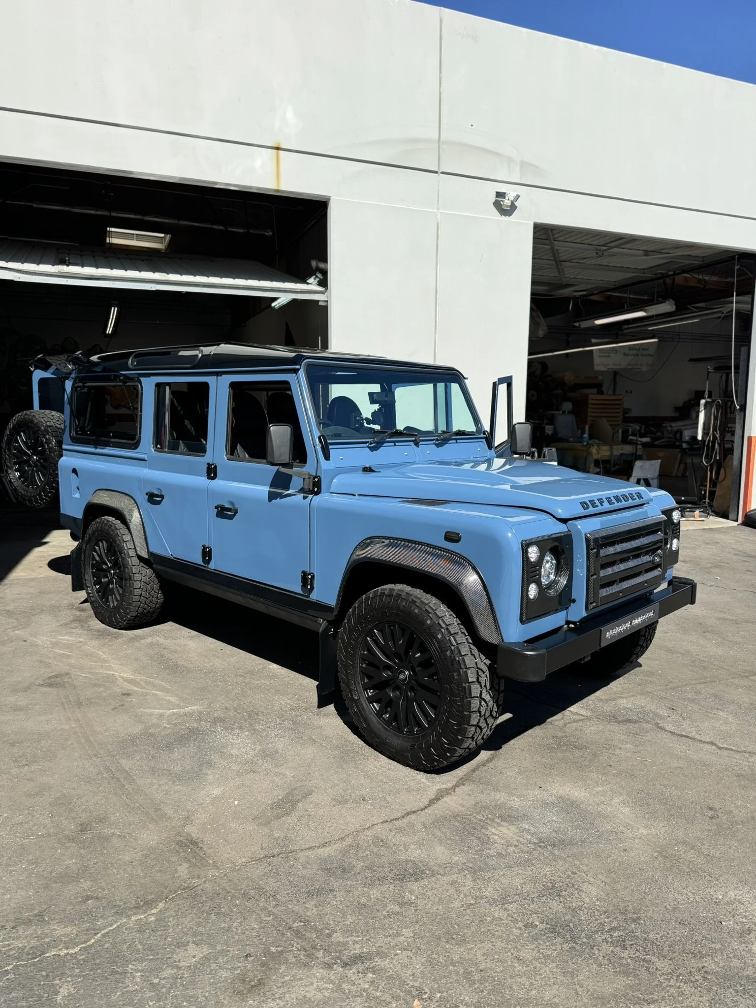 Blue Land Rover Defender parked outside a garage