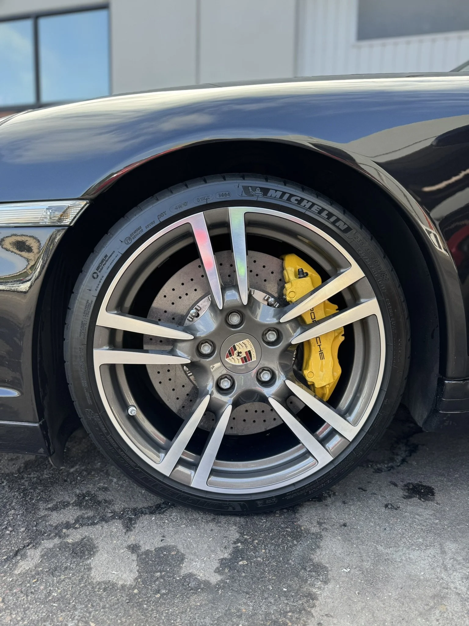 Close-up of a Porsche wheel with Michelin tire, alloy rim, and yellow brake caliper