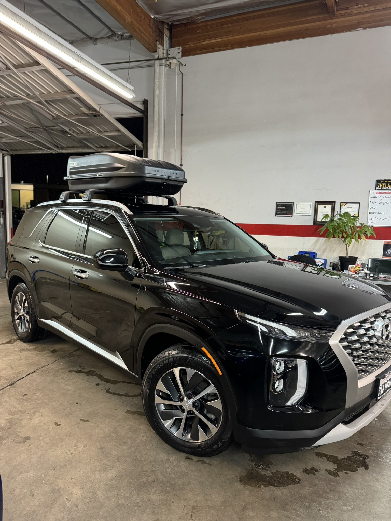 Black SUV with roof box in a garage