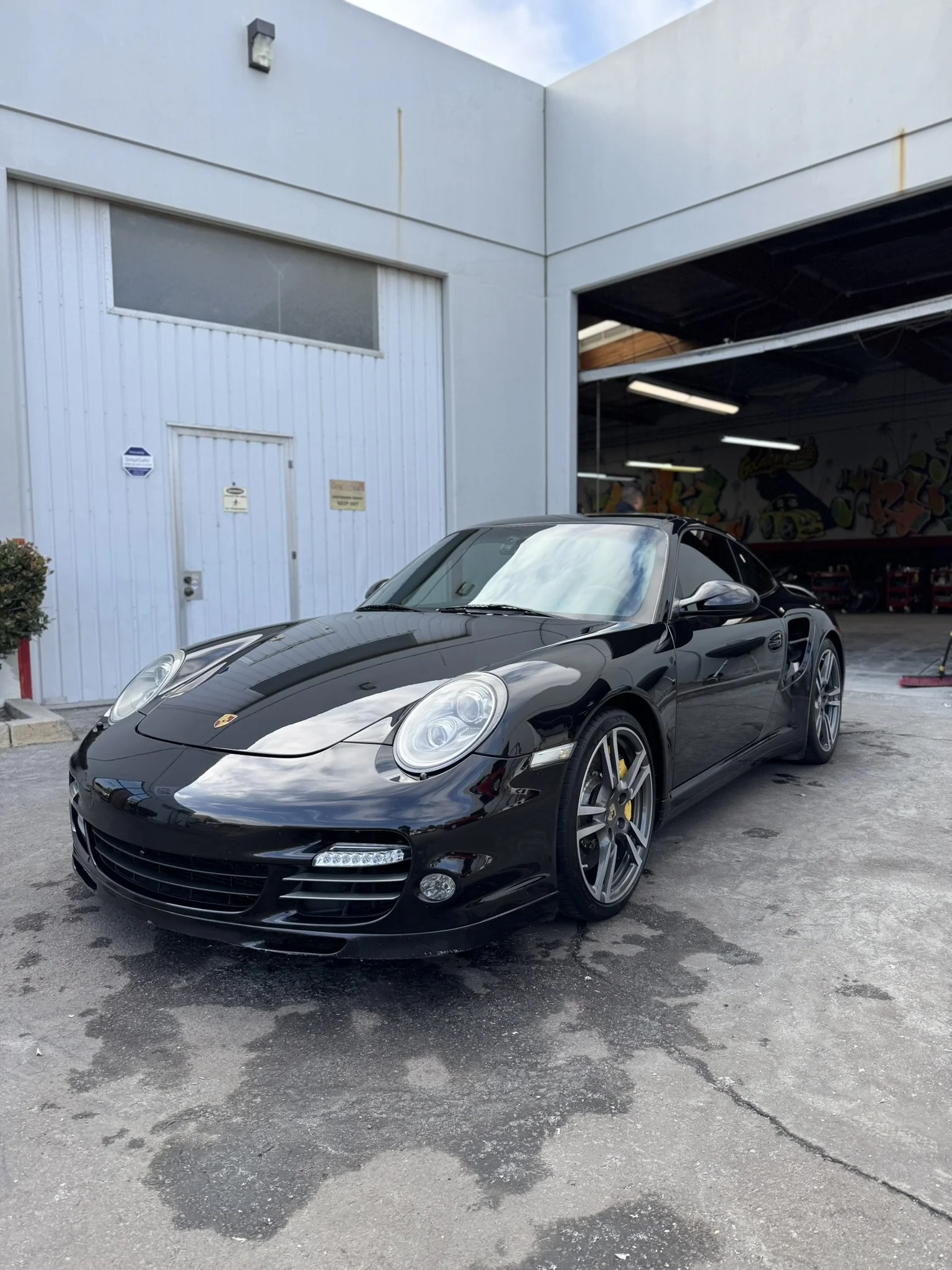 Black sports car parked outside a garage