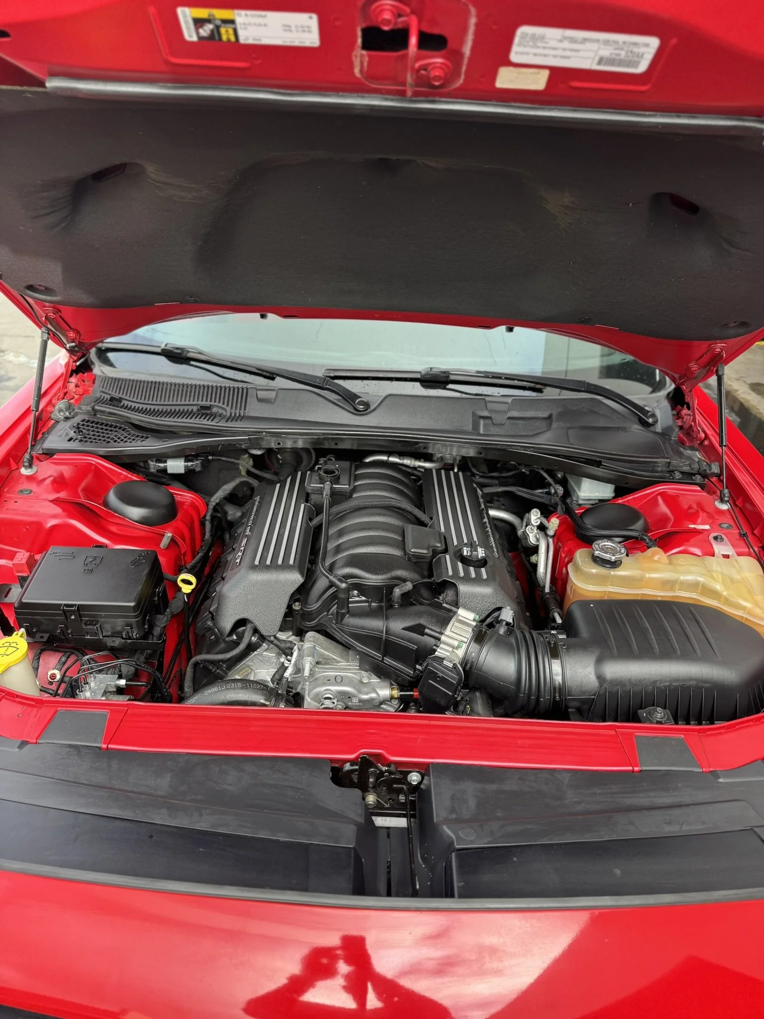 Open hood of a red car showing the engine and components.