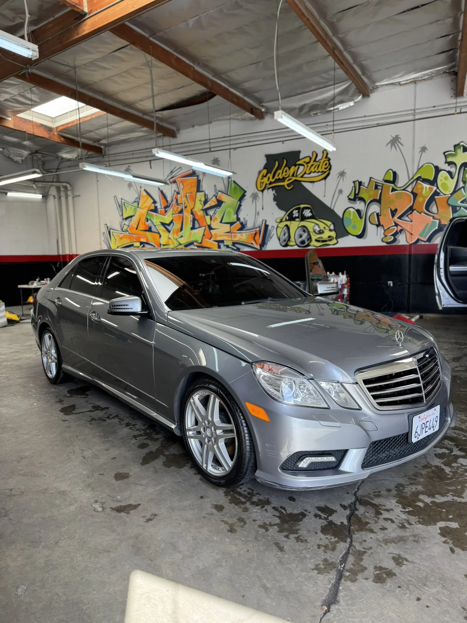 Silver Mercedes-Benz car in a graffiti-decorated garage.