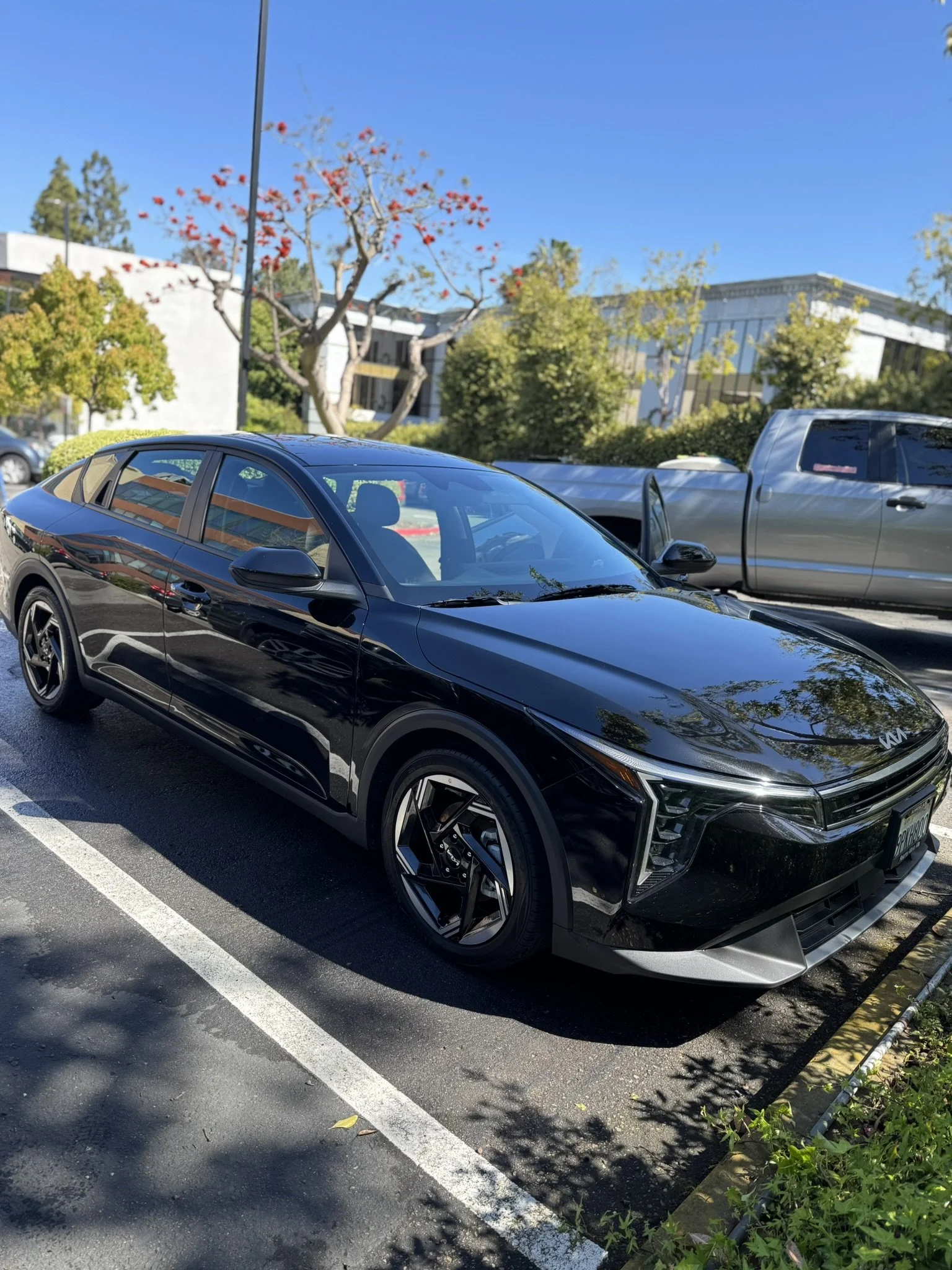 Black Kia EV6 electric car parked in a lot on a sunny day.