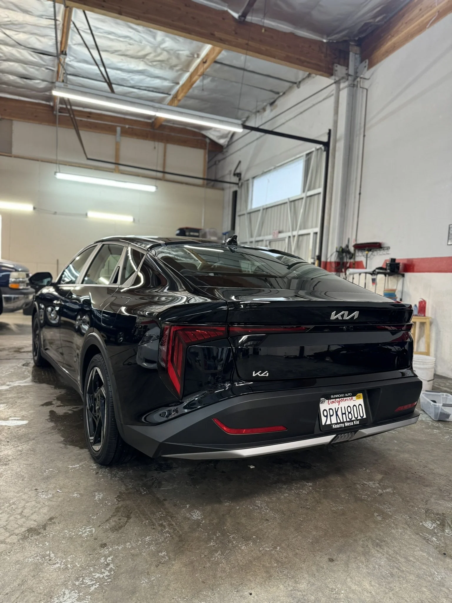 Black Kia car in a garage, rear view