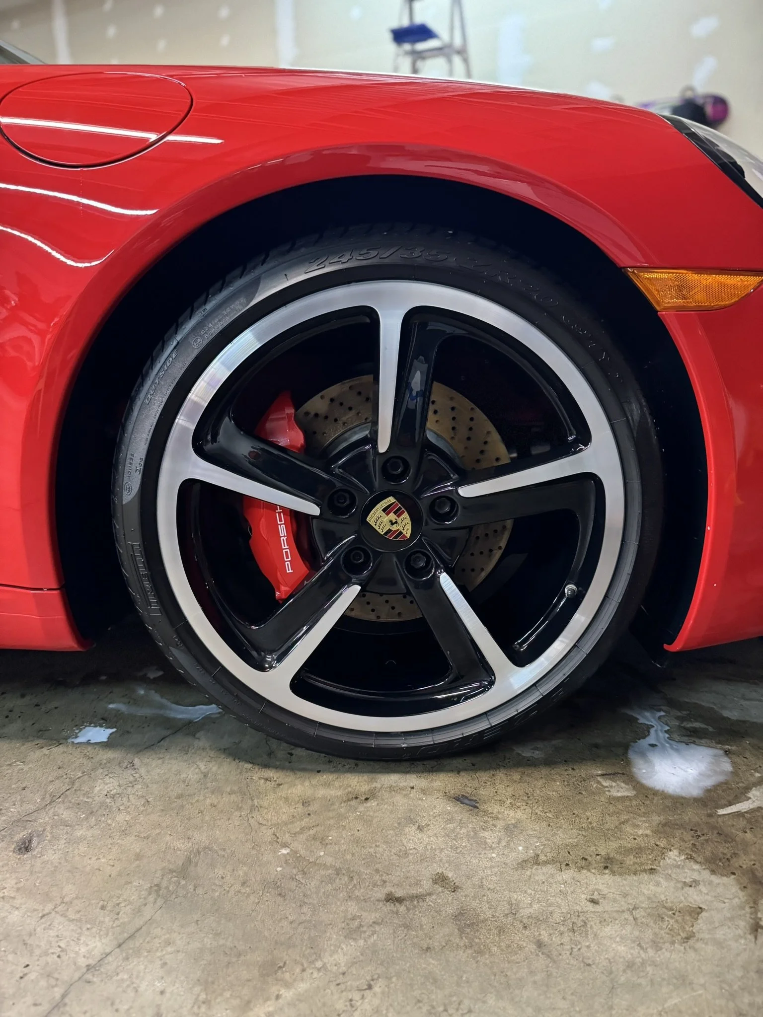 Close-up of a red sports car wheel with black alloy rim and visible brake disc.